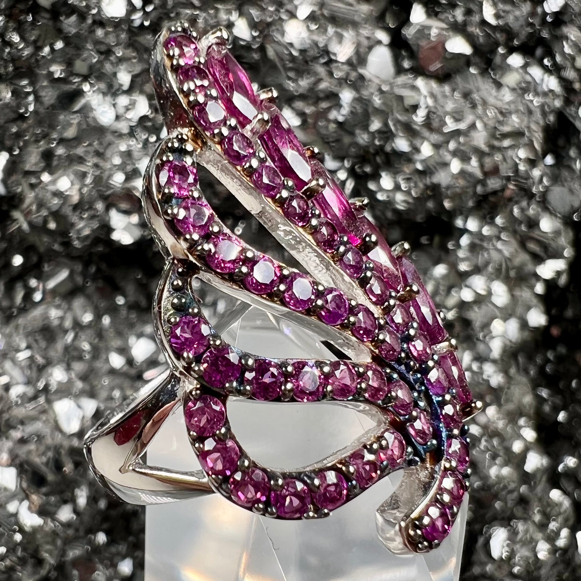 A sterling silver, feather shaped ring set with round and marquise cut rhodolite garnet stones.