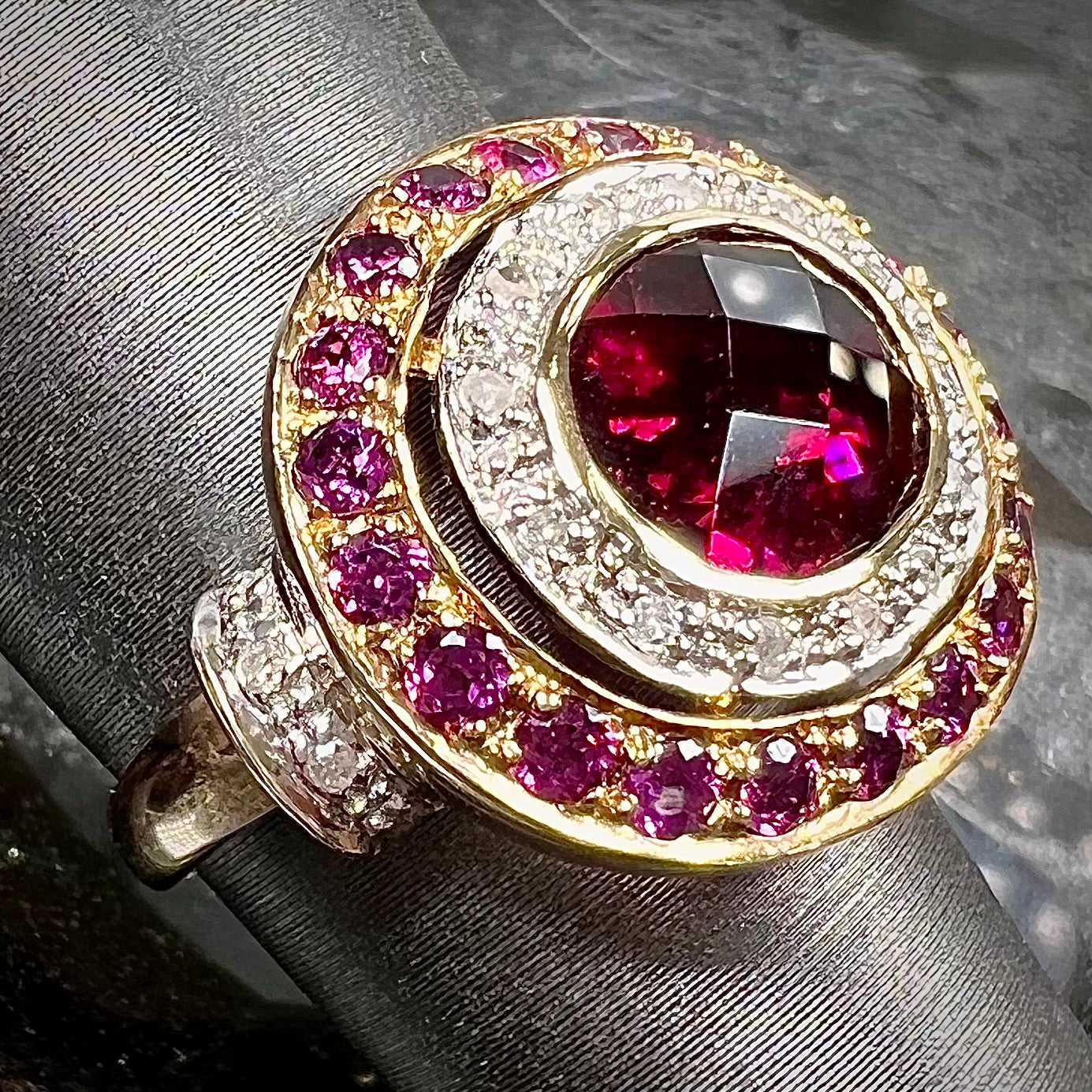 A yellow gold garnet and diamond halo ring set with a checkerboard cut rhodolite garnet center stone.