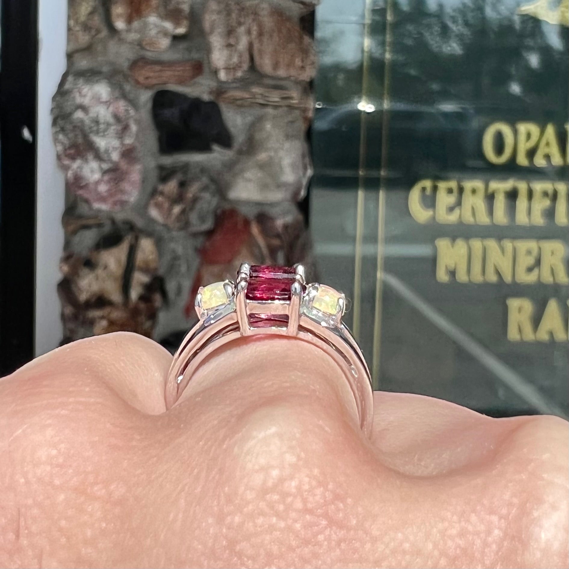A sterling silver ring set with three oval cut rhodolite garnets and four round cabochon cut Ethiopian opals.