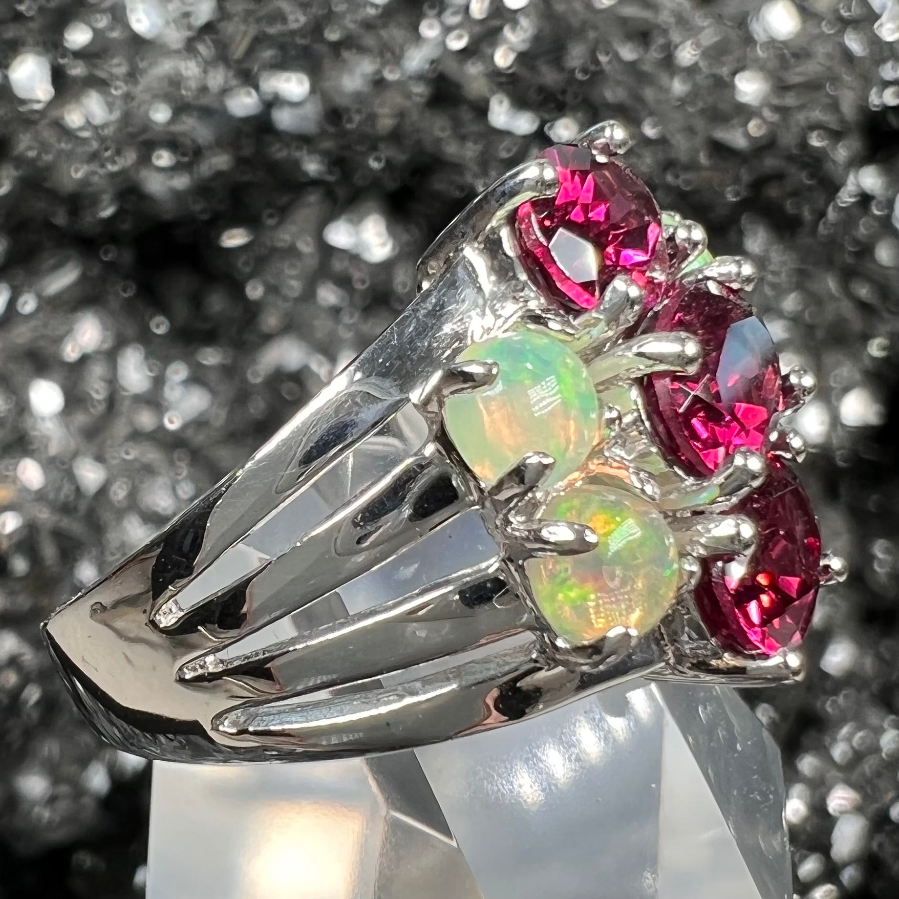 A sterling silver ring set with three oval cut rhodolite garnets and four round cabochon cut Ethiopian opals.