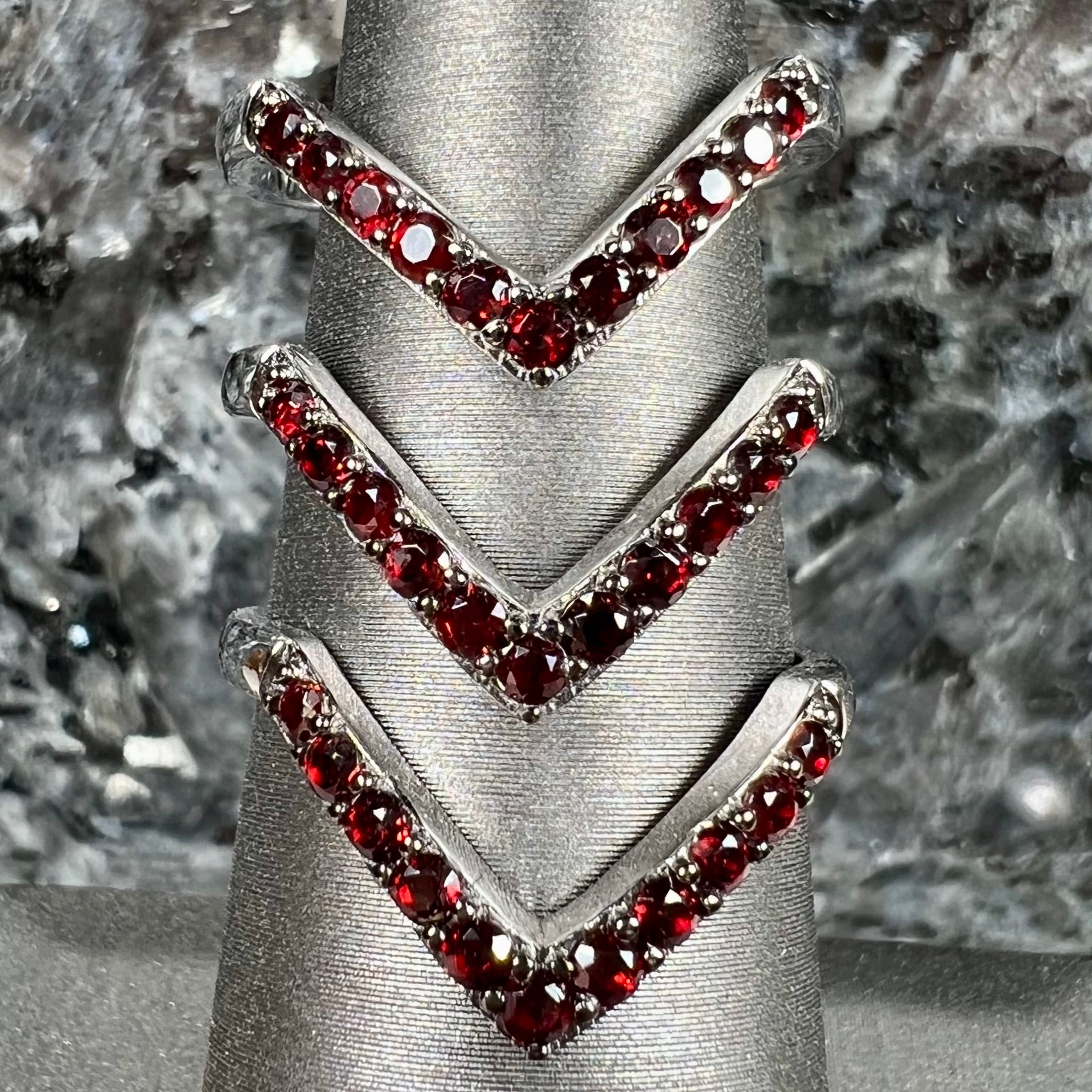 A sterling silver ring pave set with round almandine garnet stones.  The piece appears to be three rings in one.