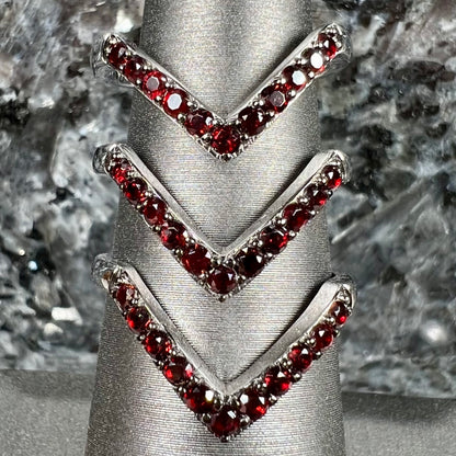 A sterling silver ring pave set with round almandine garnet stones.  The piece appears to be three rings in one.