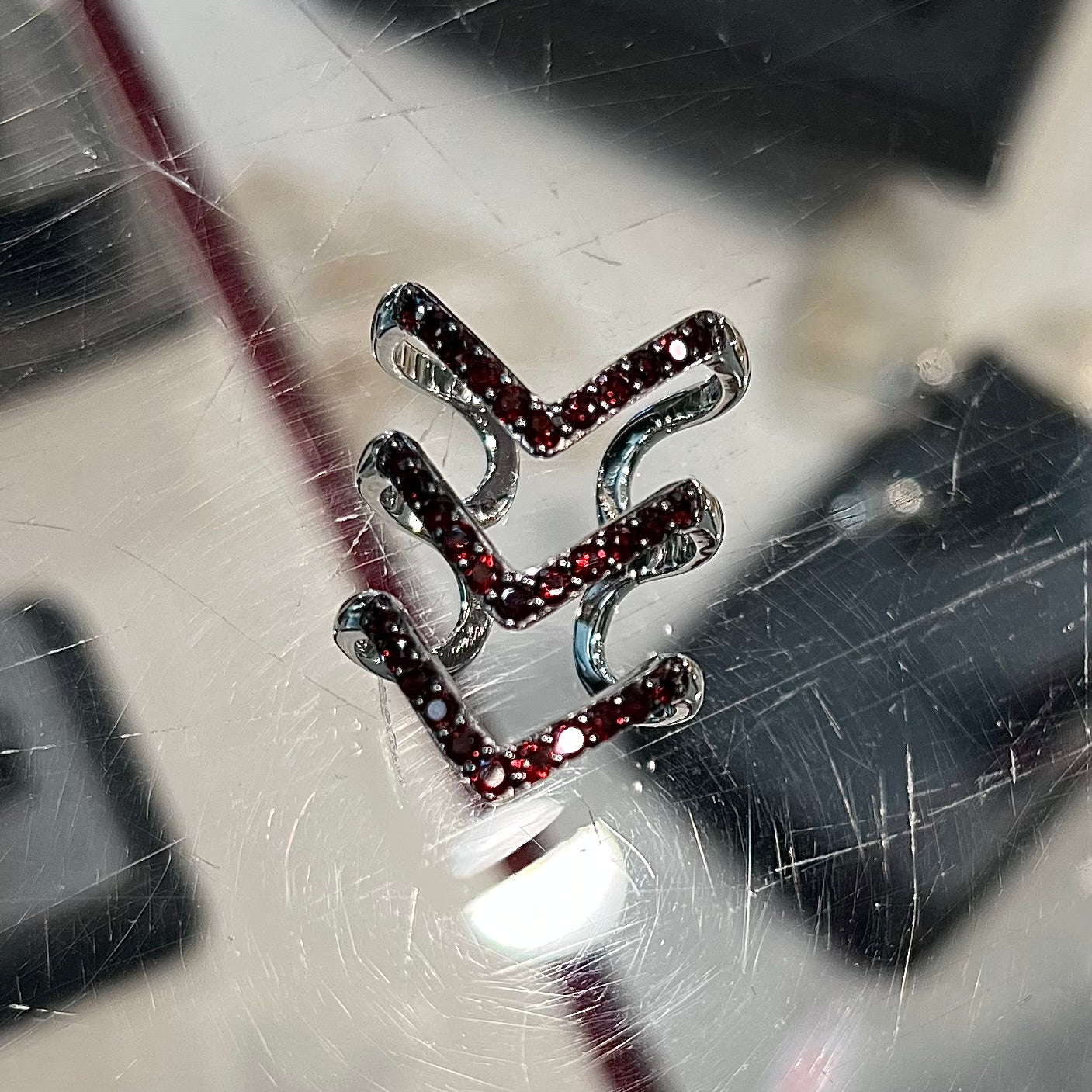 A sterling silver ring pave set with round almandine garnet stones.  The piece appears to be three rings in one.