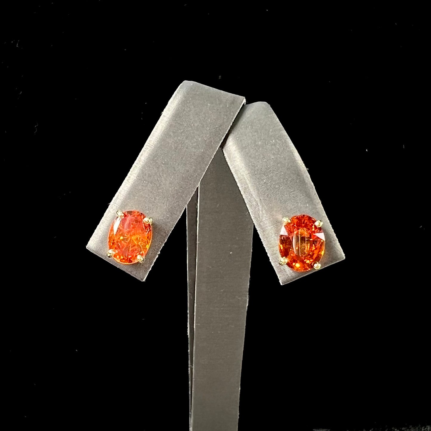 A pair of yellow gold orange hessonite garnet stud earrings.  The garnets are faceted oval cut.