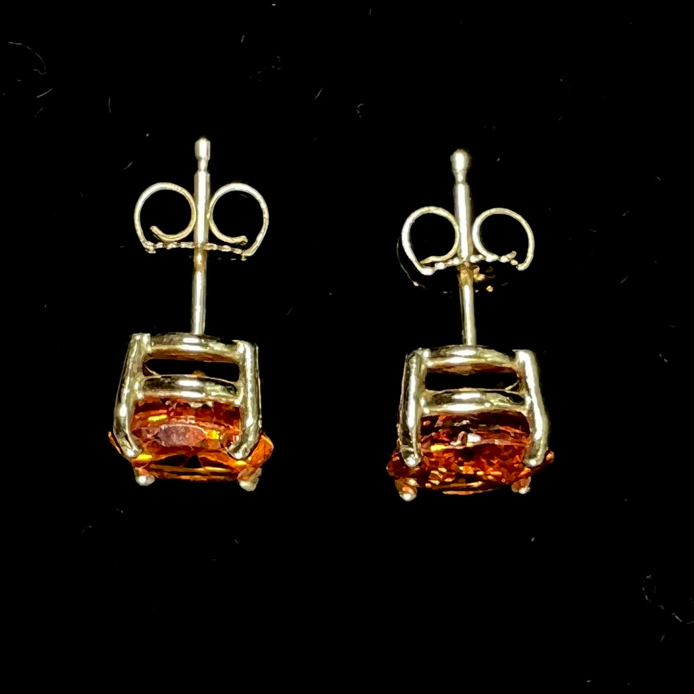 A pair of yellow gold orange hessonite garnet stud earrings.  The garnets are faceted oval cut.