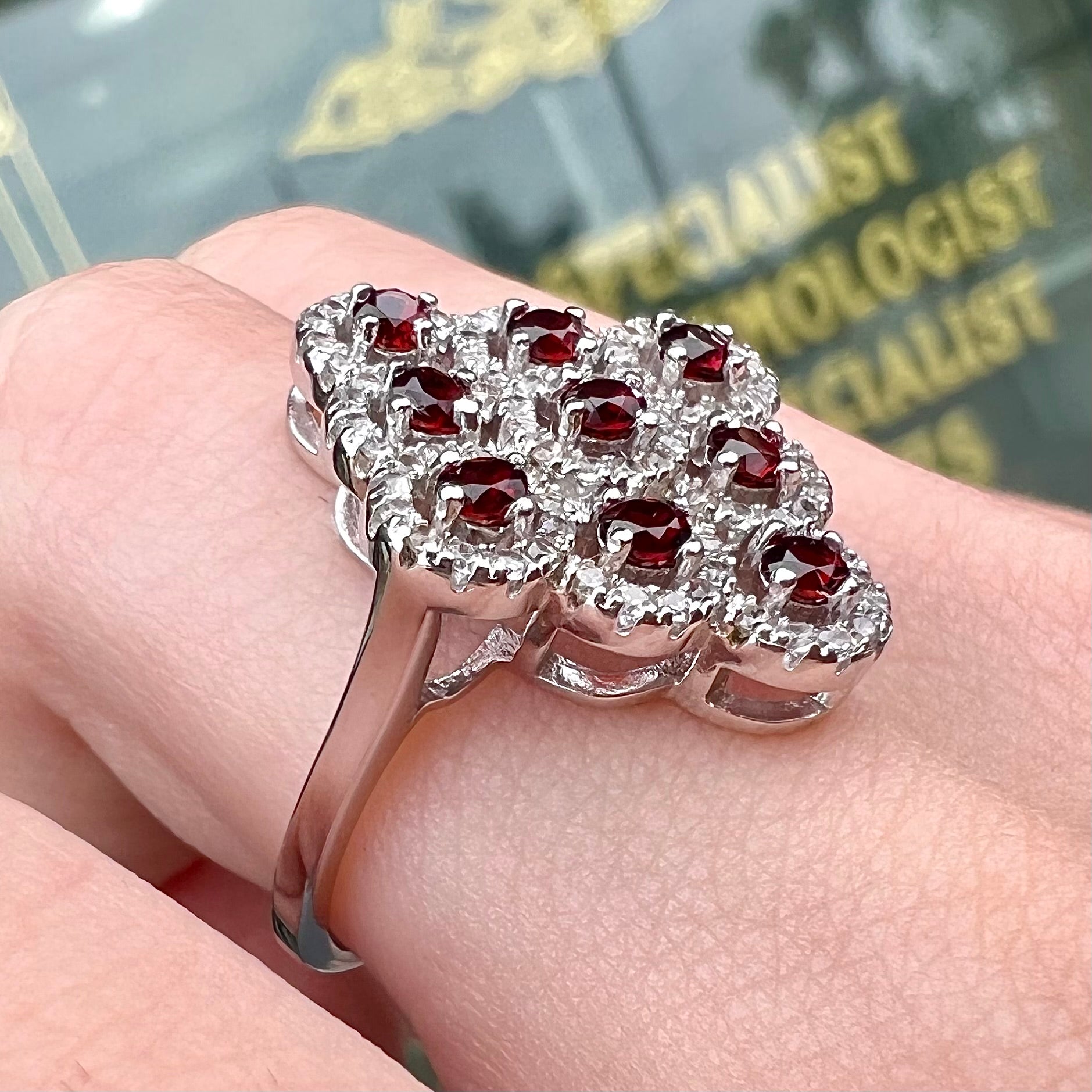 A sterling silver cluster ring set with round almandine garnet main stones and white zircon accents.