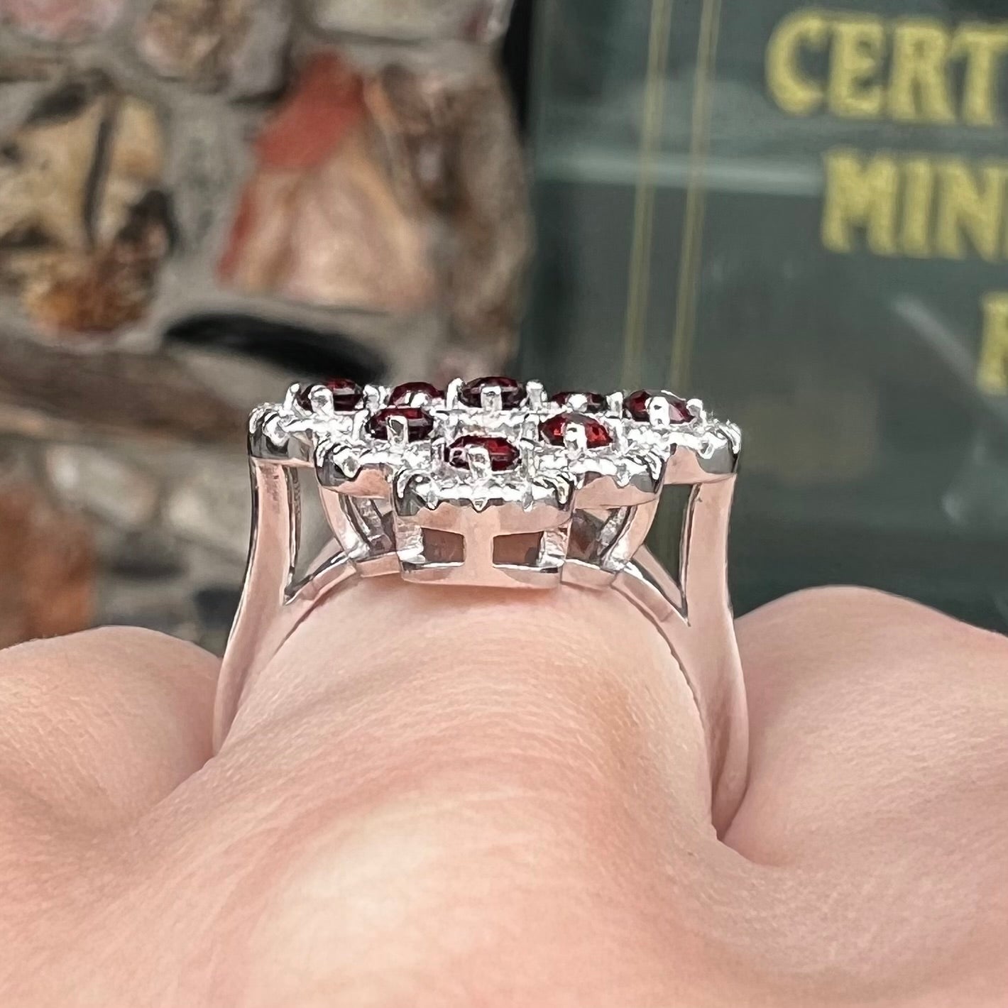 A sterling silver cluster ring set with round almandine garnet main stones and white zircon accents.