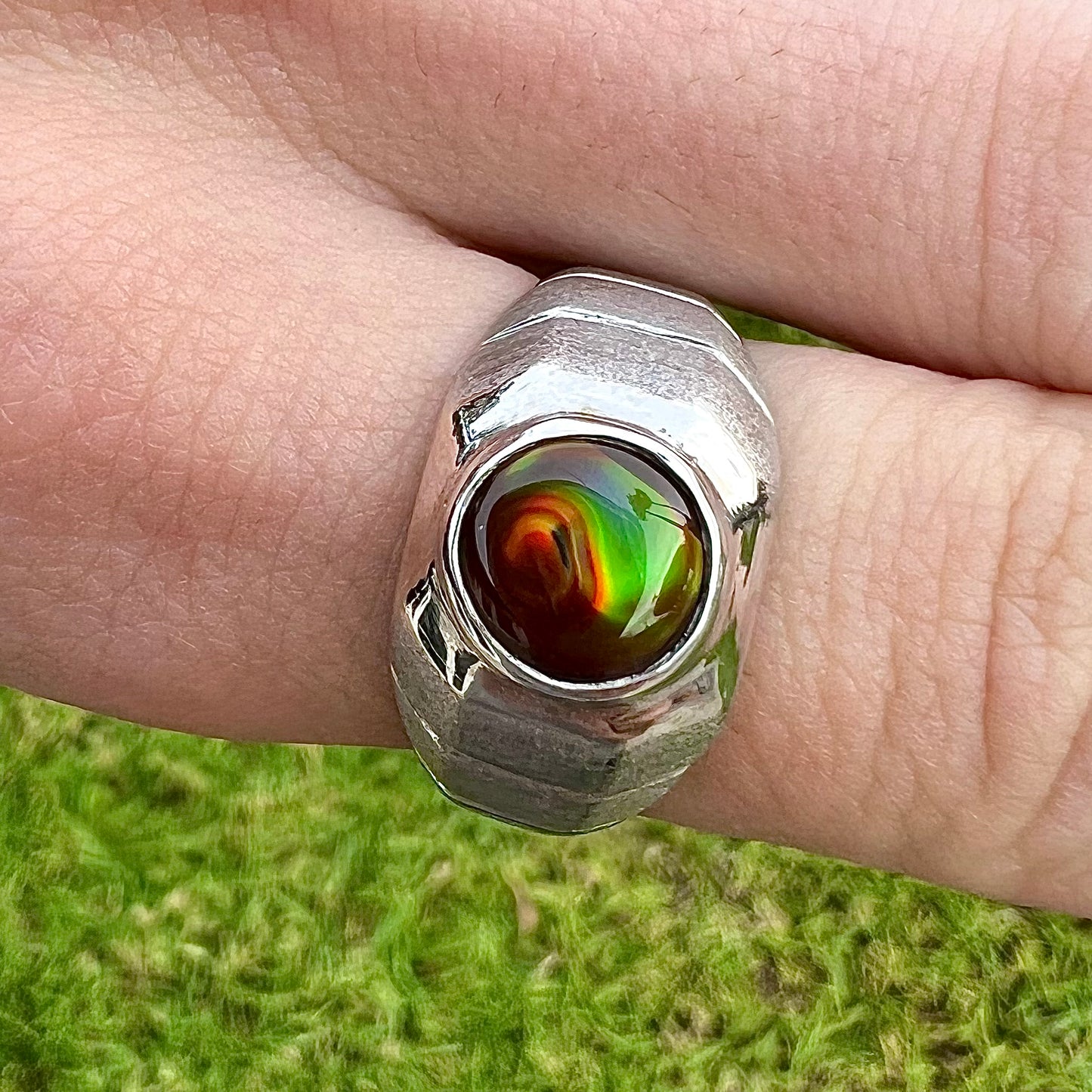 A round cabochon cut red and green fire agate set in a brushed metal white gold men's ring.