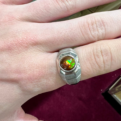 A round cabochon cut red and green fire agate set in a brushed metal white gold men's ring.