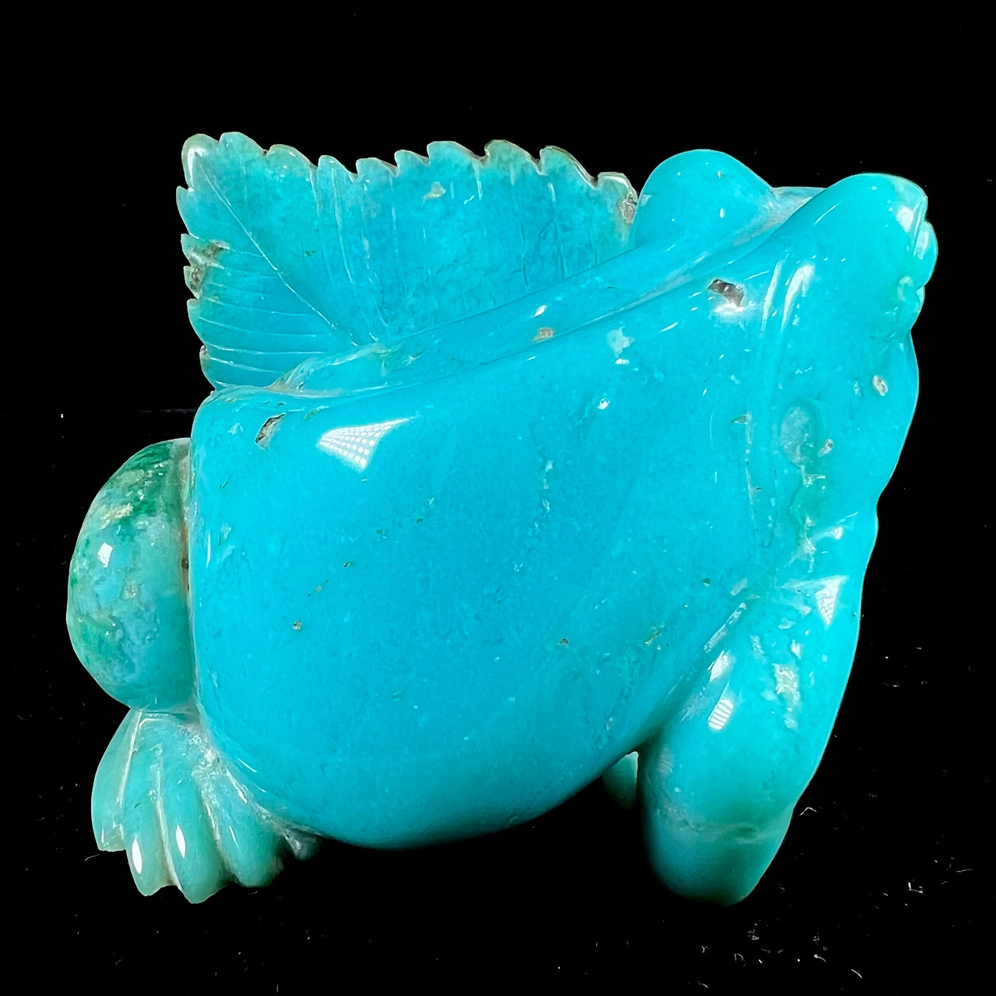 A stone frog peeking from behind a leaf carved from gem silica grade chrysocolla by artist, Ron Stevens.