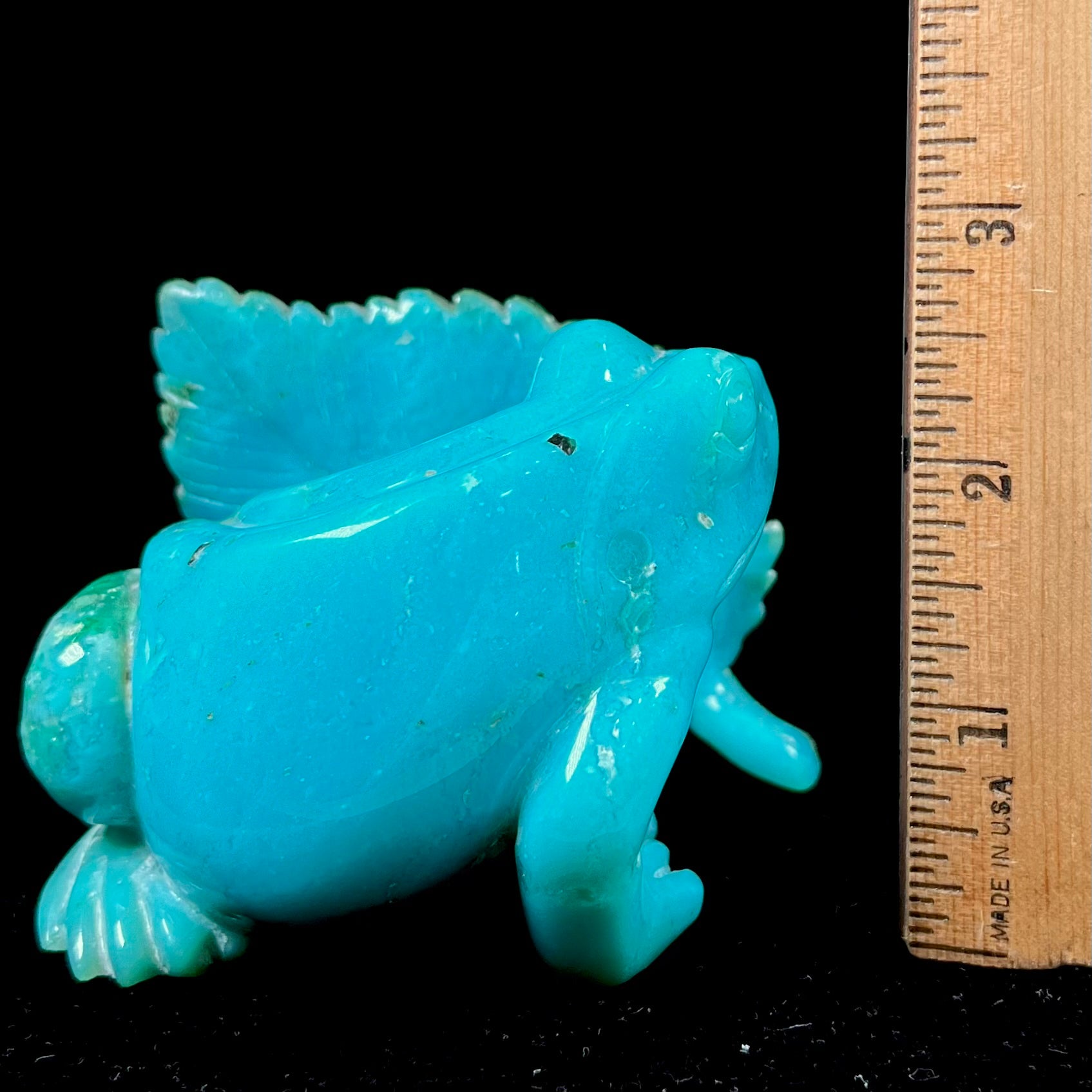 A stone frog peeking from behind a leaf carved from gem silica grade chrysocolla by artist, Ron Stevens.