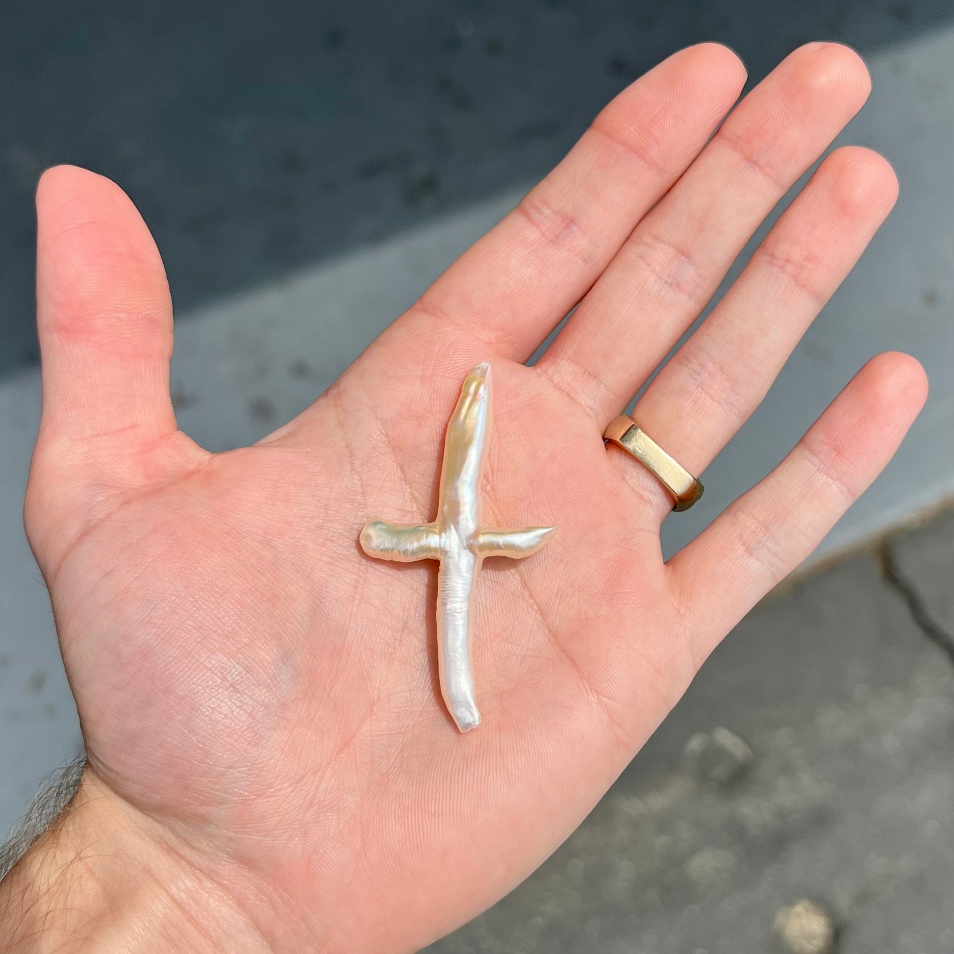 A loose, cultured dark cream colored freshwater pearl cross with pink overtones.