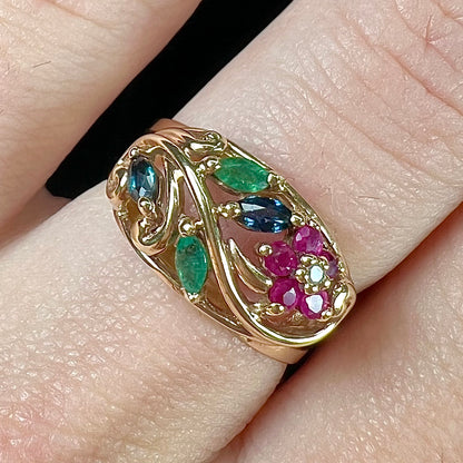 A yellow gold ladies' ring featuring the motif of a flower with leaves set with emeralds, rubies, sapphires, and a  diamond.