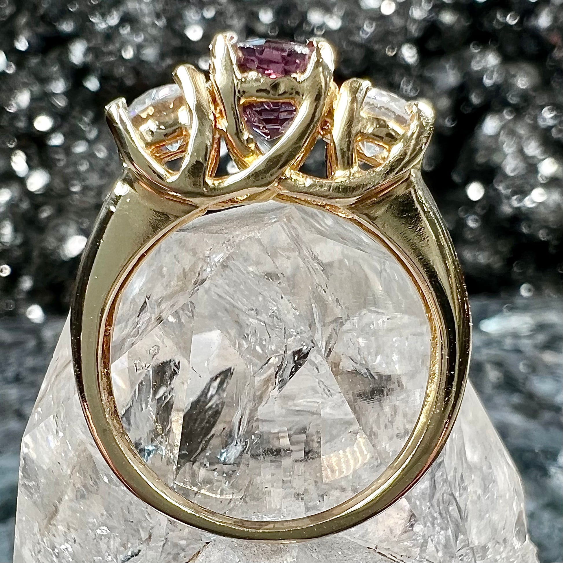 A yellow gold three stone ring set with two round cut white zircons and one cushion cut purple spinel.