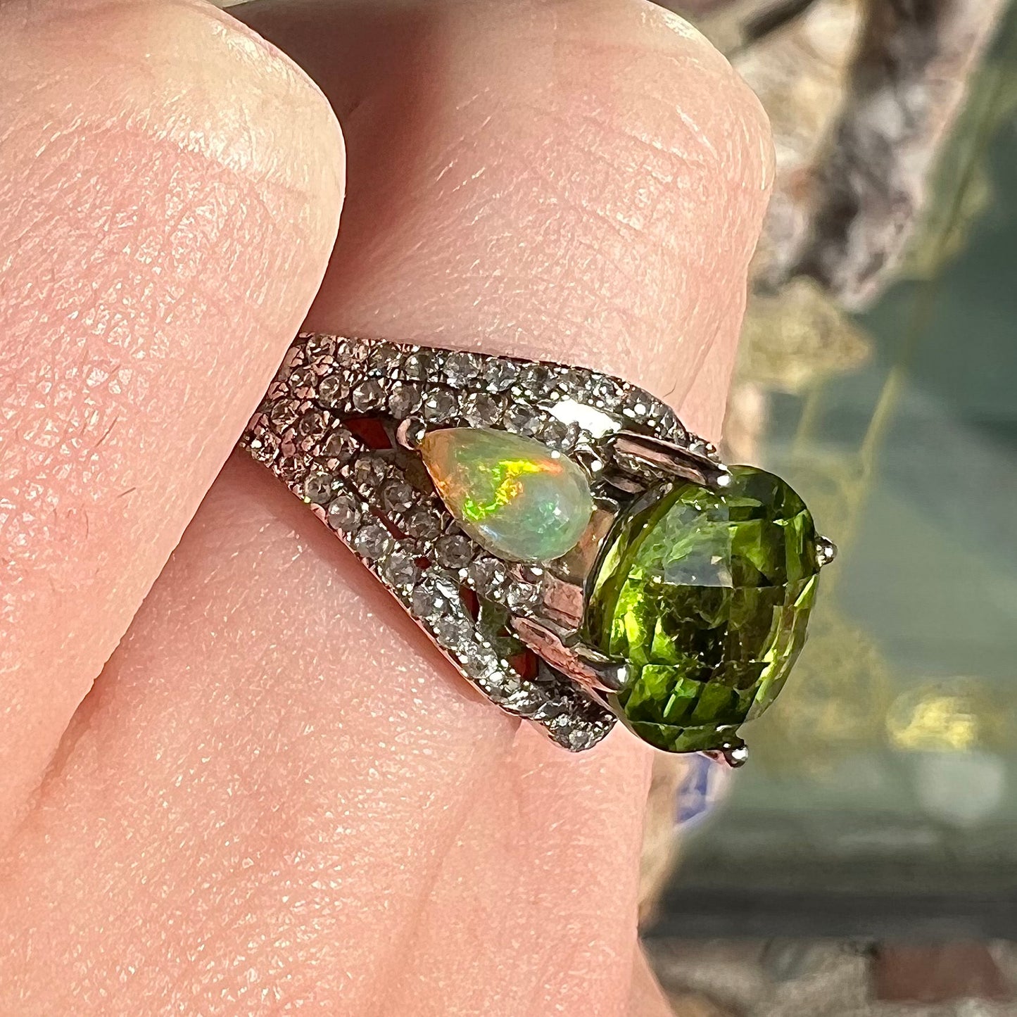 A sterling silver ring set with one large round peridot stone set between two pear shape cabochon Ethiopian opals.  Cubic zirconia stones line the ring.