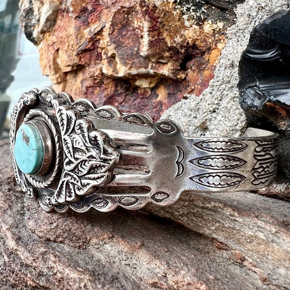 A base metal cuff bracelet set with a round cabochon cut imitation blue turquoise stone.