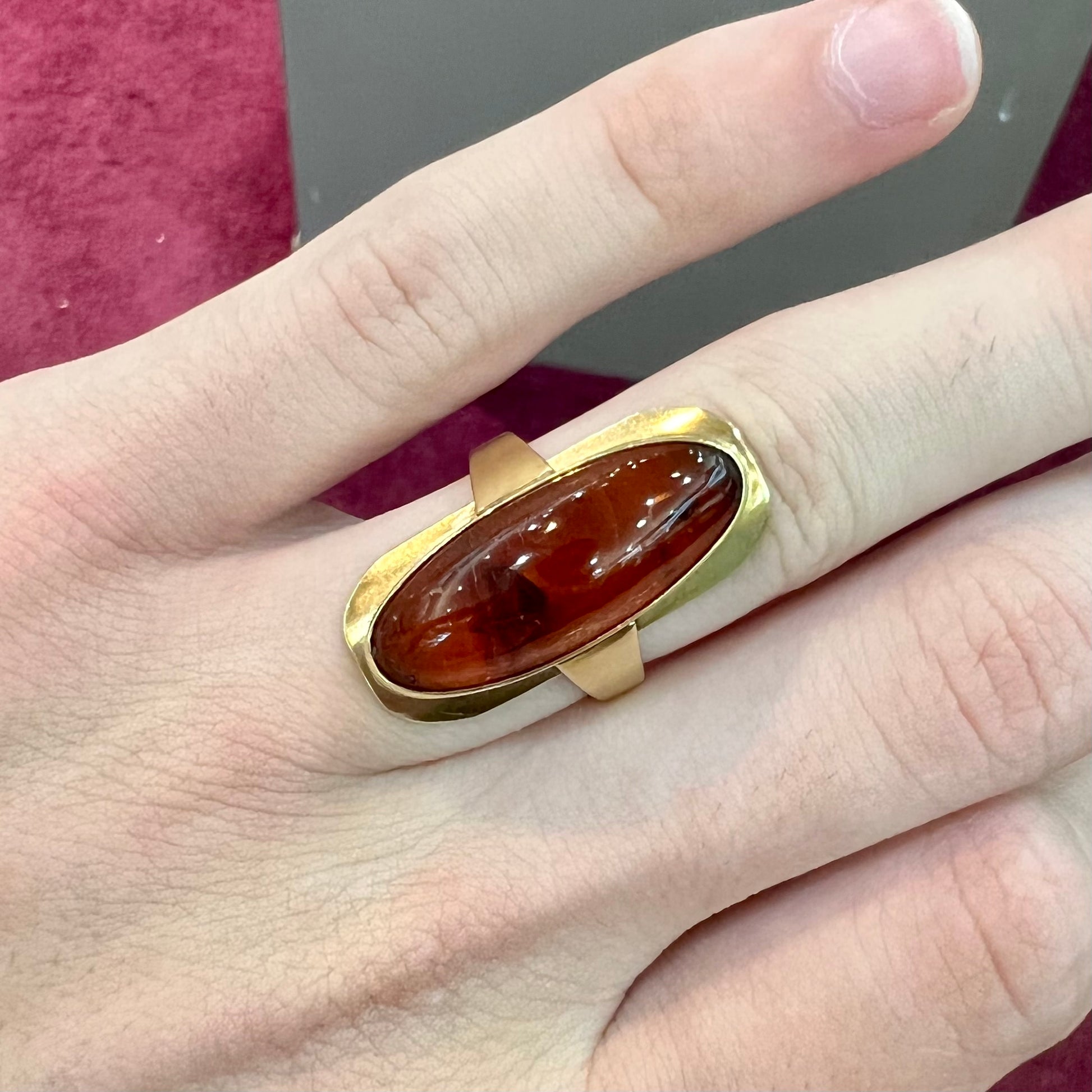 An oval cabochon cut Baltic amber stone set in a yellow gold ring and stamped "AMBER GUILD."