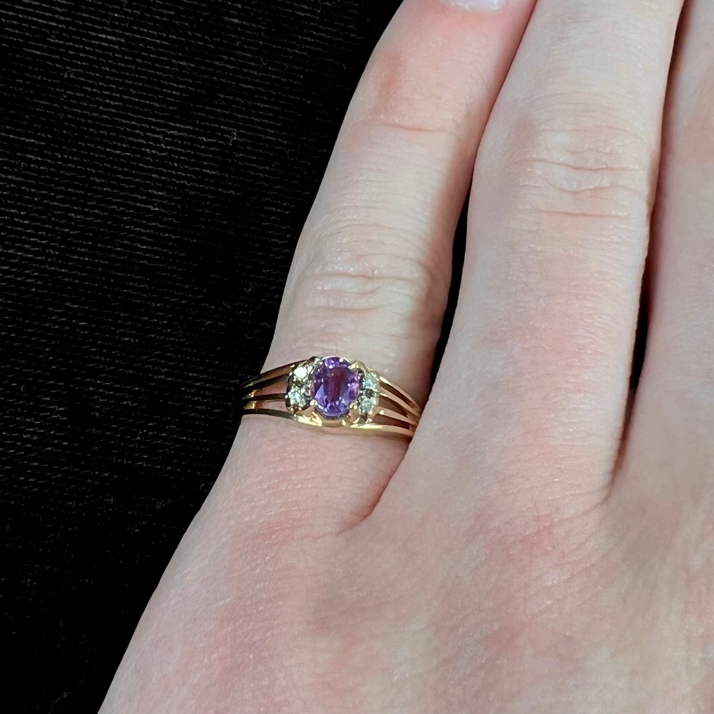 A ladies split shank gold ring set with an oval cut amethyst and round brilliant diamond accents.