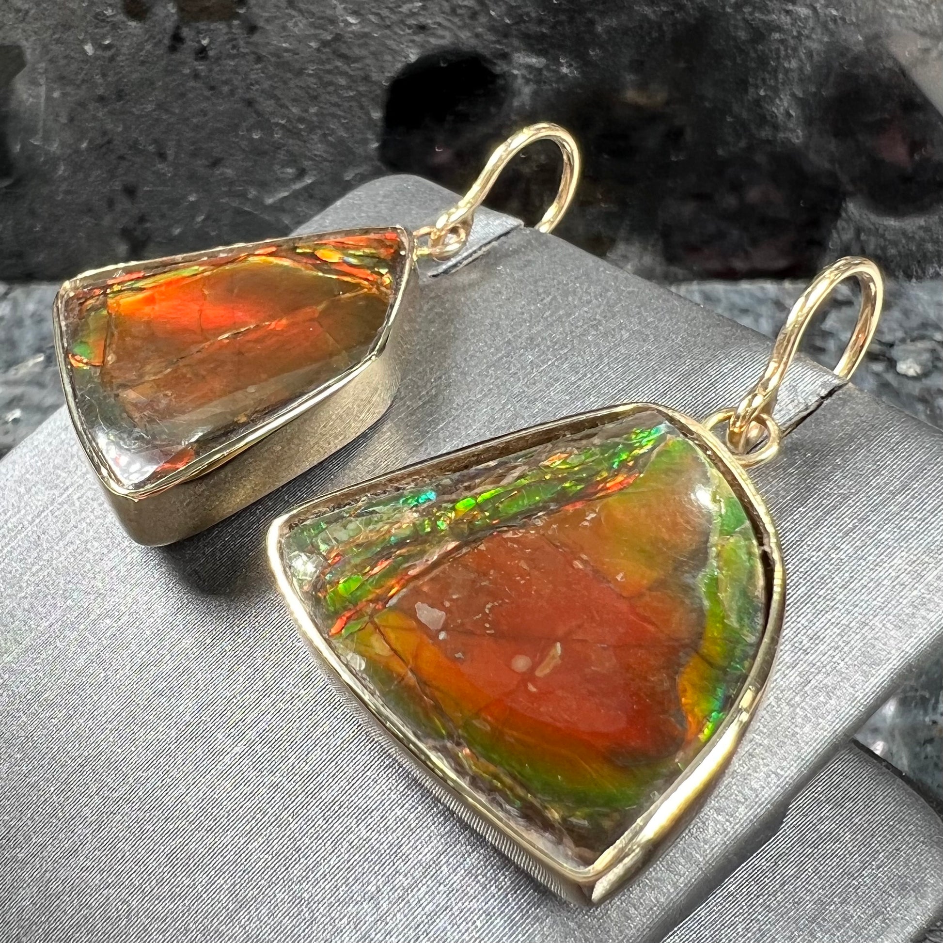 Yellow gold French wire dangle earrings bezel set with two polished freeform cut red ammolite fossils.