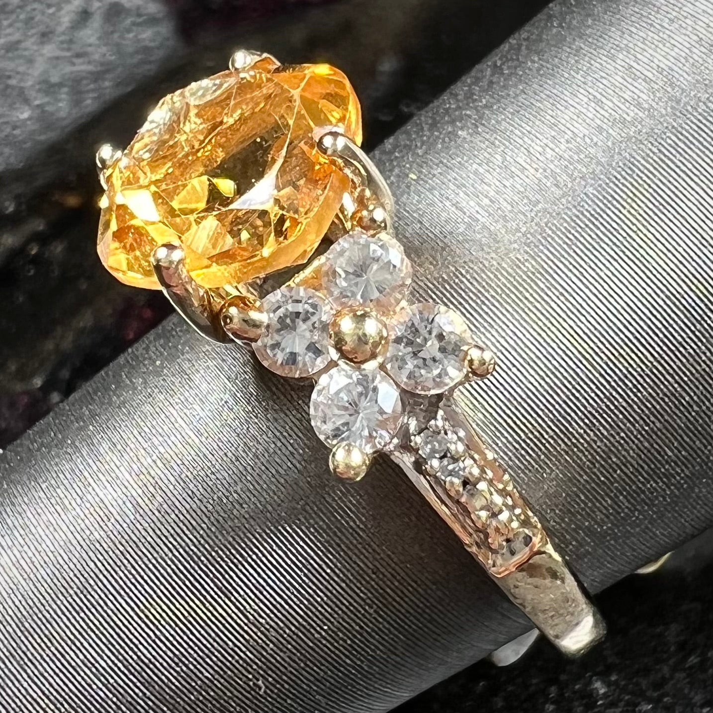 A cushion cut citrine set in a yellow gold ring with four round white sapphires and two diamonds on each side.
