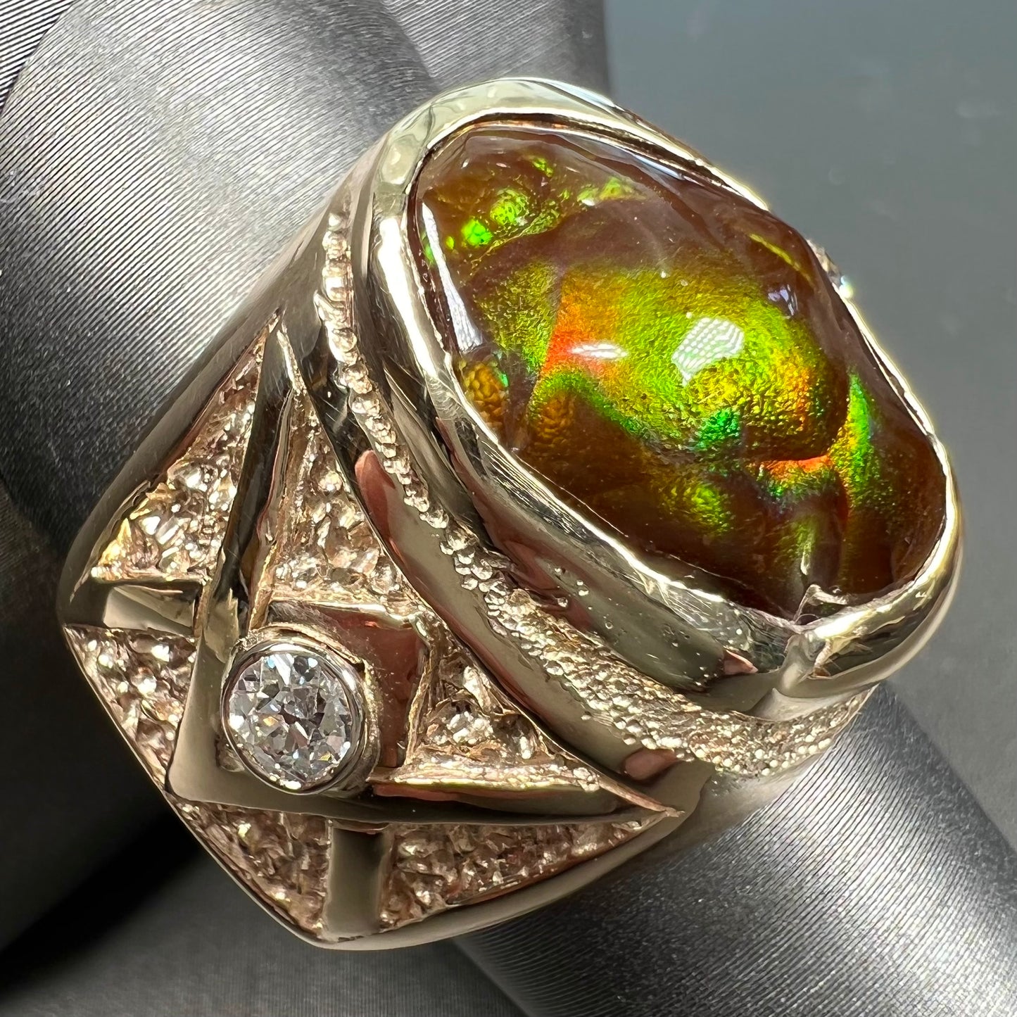 A men's solid yellow gold fire agate and diamond ring.  The fire agate displays predominantly red and green.