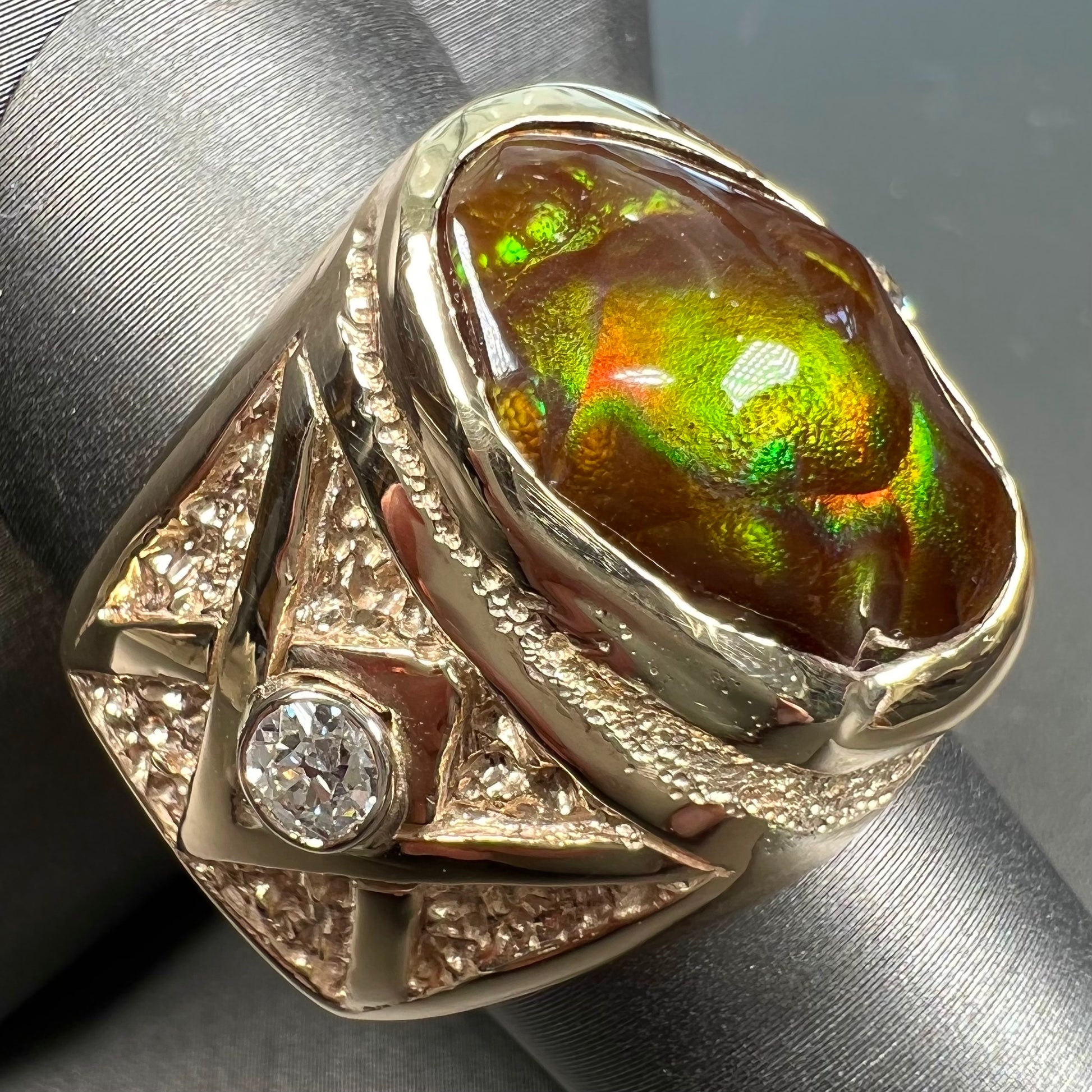 A men's solid yellow gold fire agate and diamond ring.  The fire agate displays predominantly red and green.