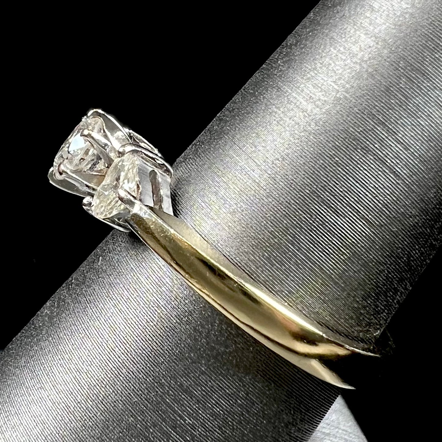 A ladies' three stone diamond ring.  The center diamond is a round brilliant cut, and the two accents are heart shaped diamonds.