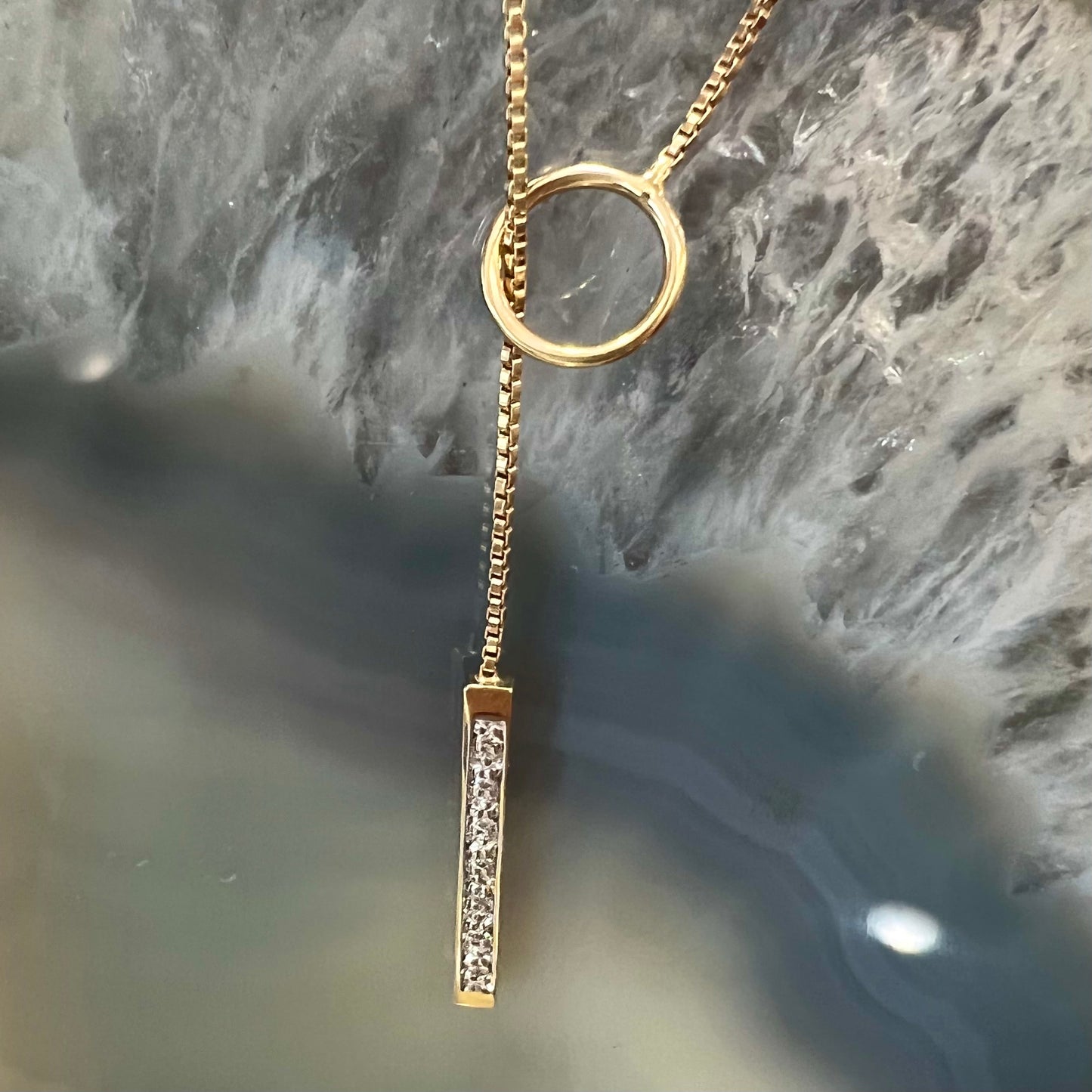 A yellow gold diamond lariat necklace on a 1mm wide box chain.  The lariat is double sided.