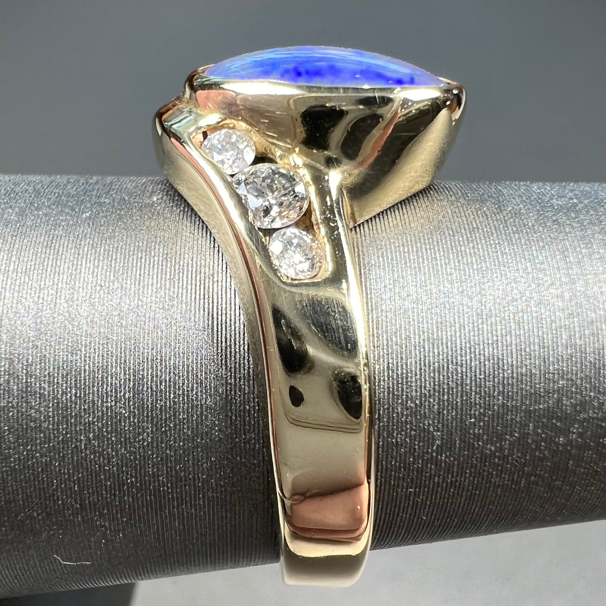 A yellow gold ring set with diamonds and a Lightning Ridge black opal from Australia.