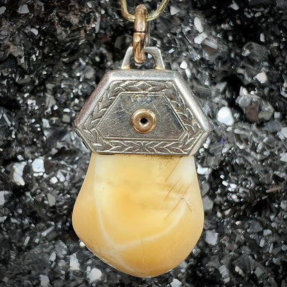 An elk tooth that has been fashioned into a blue enameled gold pendant.  There is a decorative elk head cast in yellow gold set on the piece.