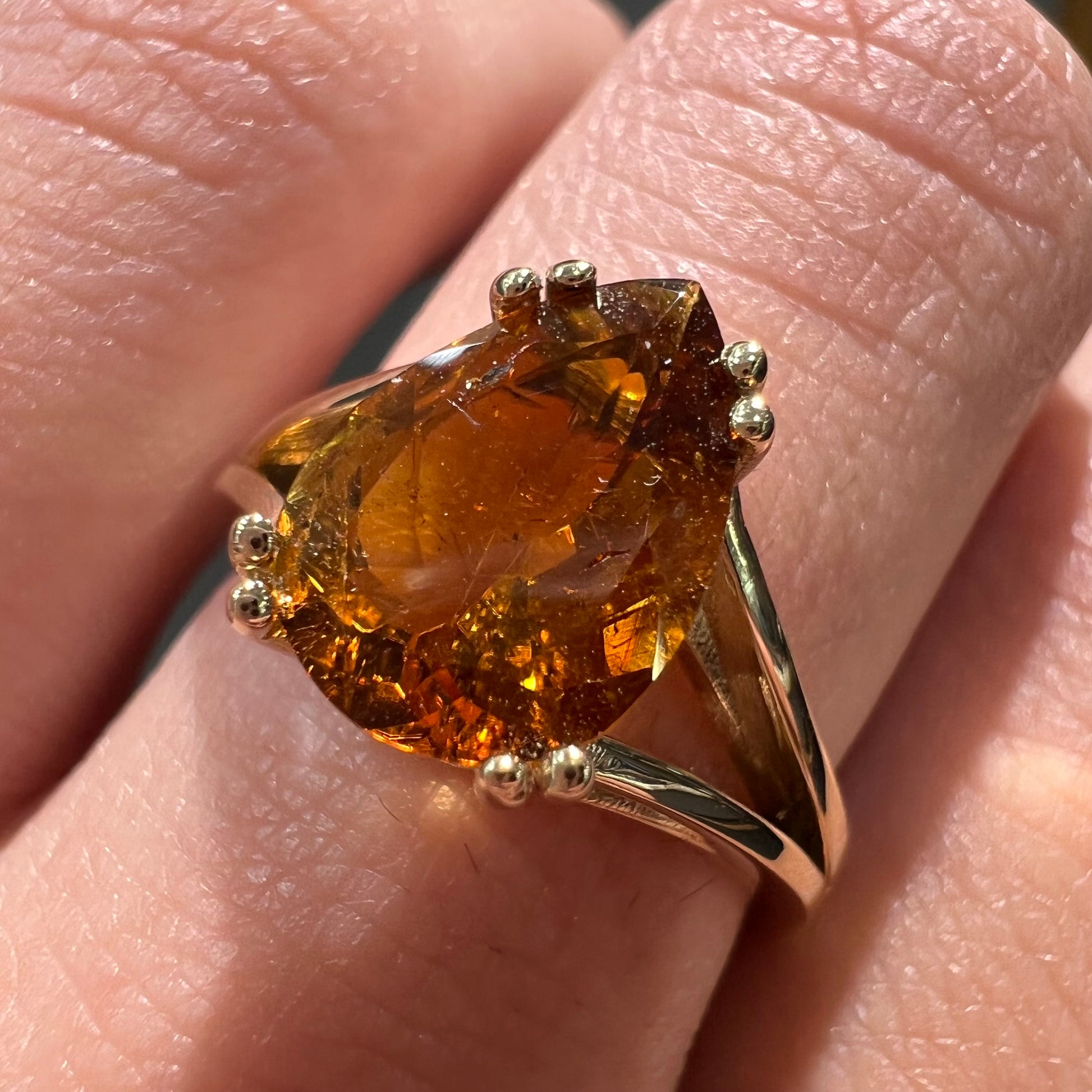 A gold split Euro shank solitaire ring set with an orange pear shape hessonite garnet stone.