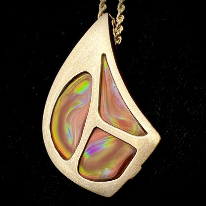A men's gold pendant set with three fire agate stones.  The fire agate resembles an oil slick puddle.