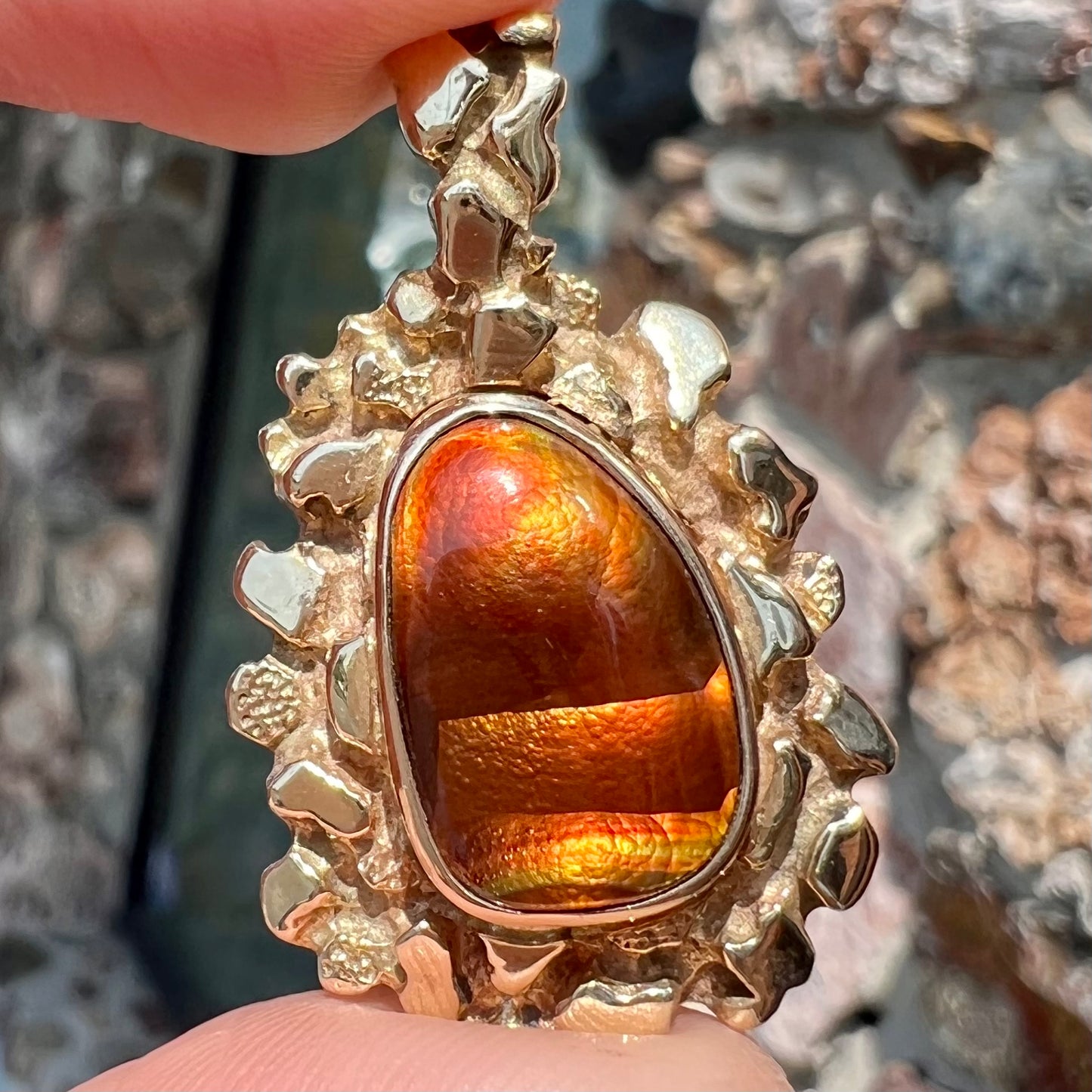 A gold nugget style pendant set with a freeform cabochon cut fire agate stone.