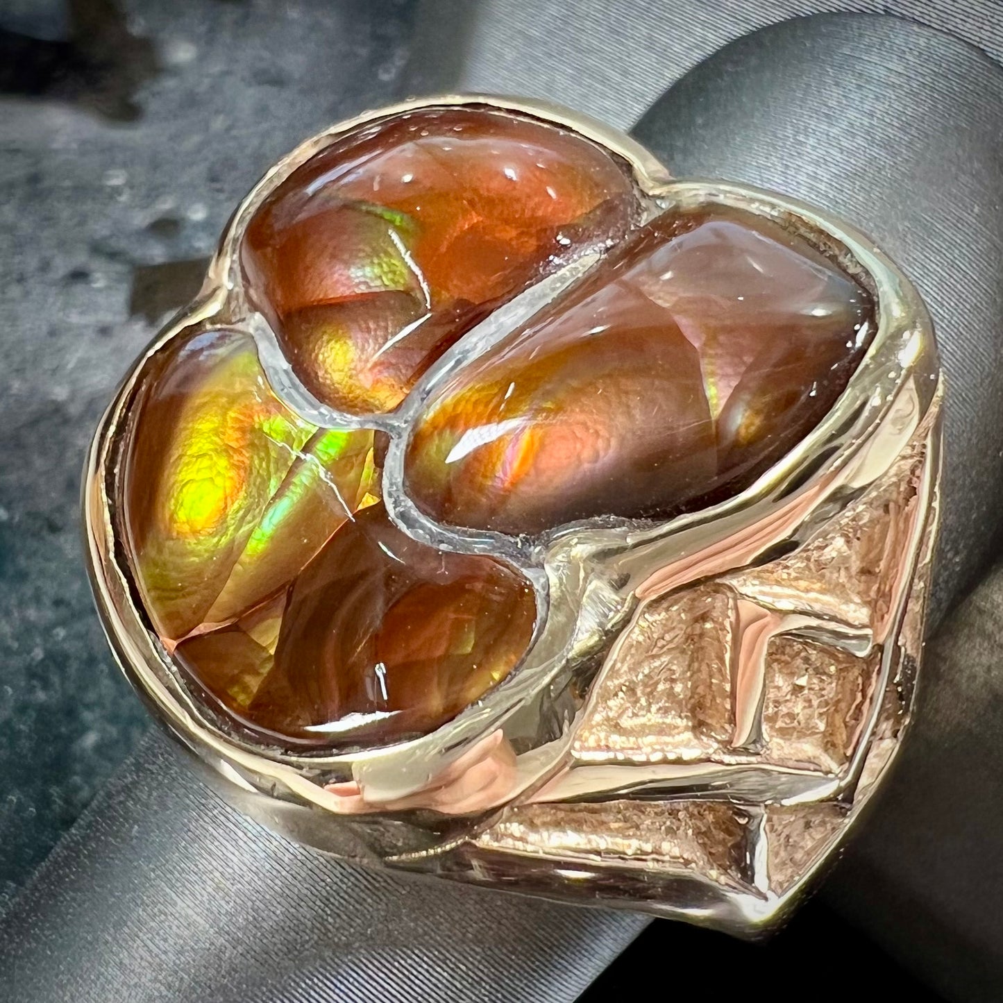 A men's yellow gold ring inlaid with three freeform cut fire agate stones.