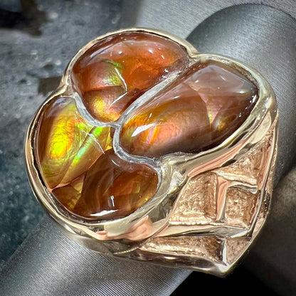 A men's yellow gold ring inlaid with three freeform cut fire agate stones.