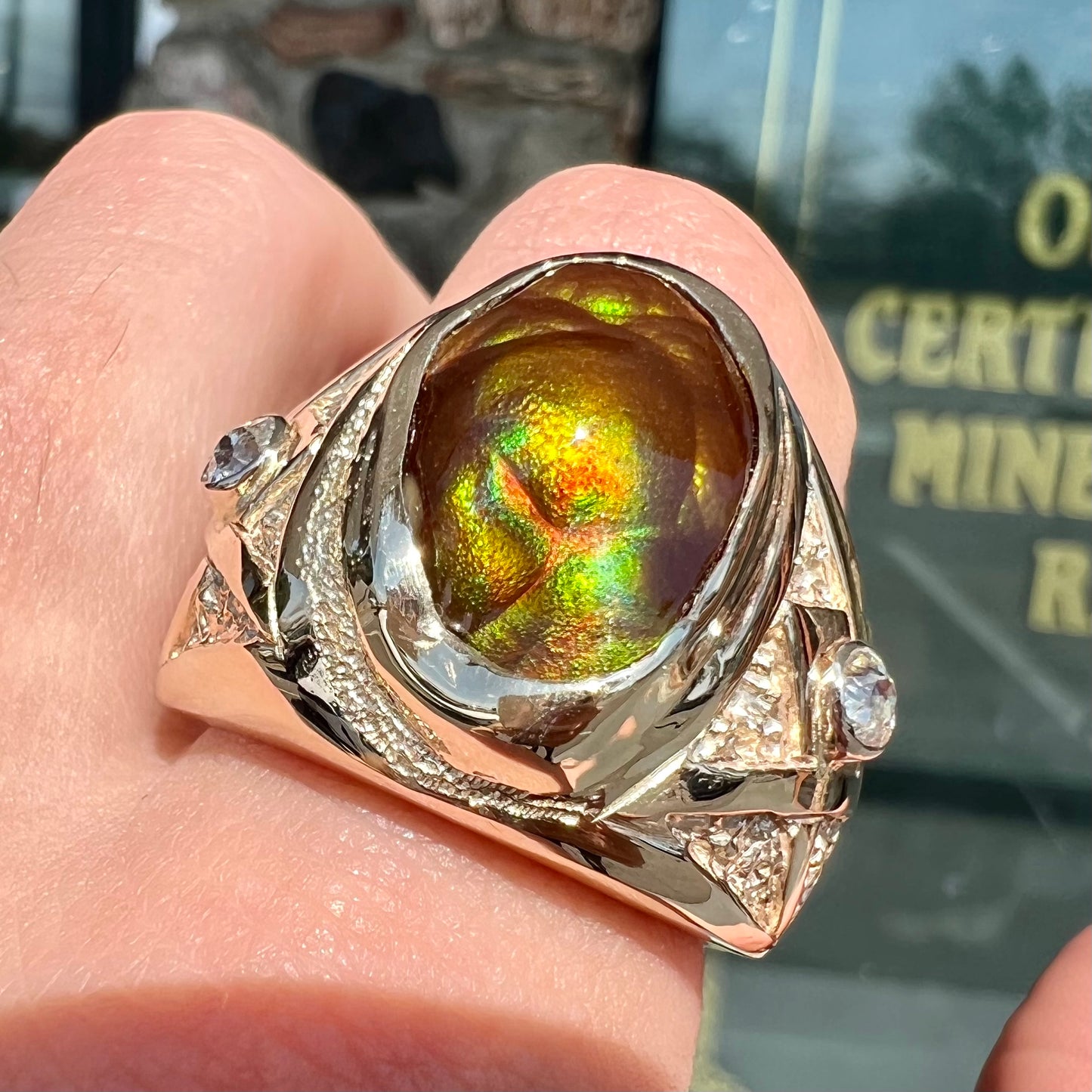 A men's solid yellow gold fire agate and diamond ring.  The fire agate displays predominantly red and green.