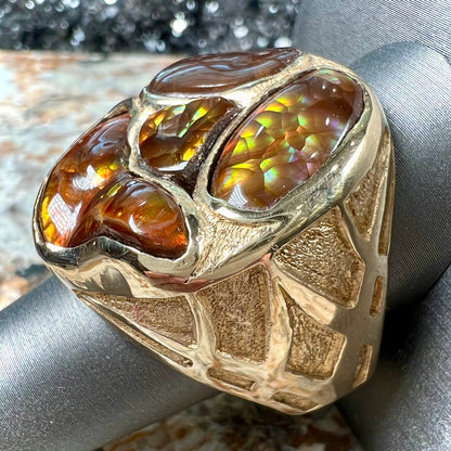 A yellow gold men's thug ring set with four fire agate stones resembling a spooky face.