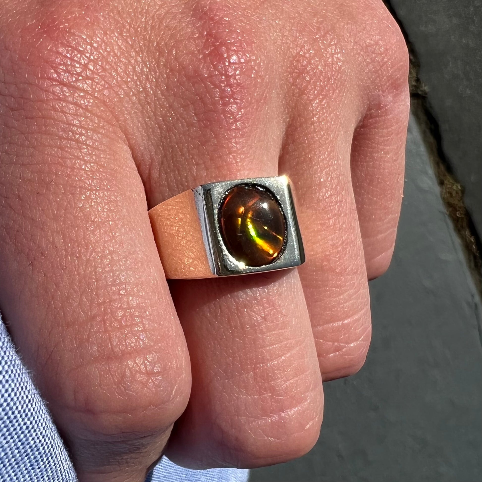 A men's yellow gold flush set fire agate solitaire ring.  The fire agate displays flashes of green, orange, and yellow.