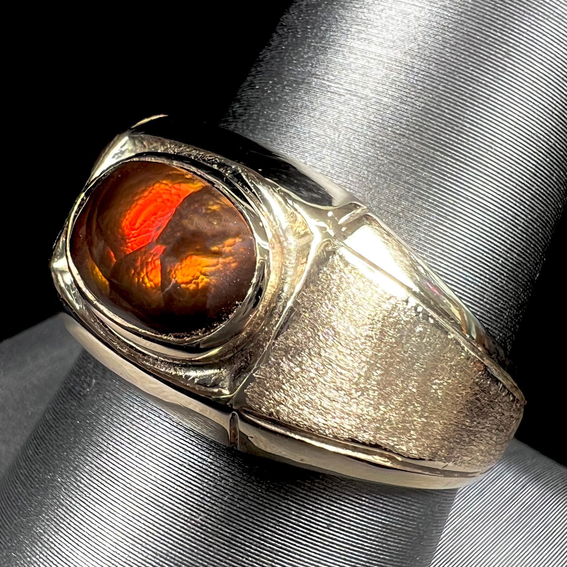 A yellow gold men's fire agate solitaire ring.  The fire agate is red with green undertones.