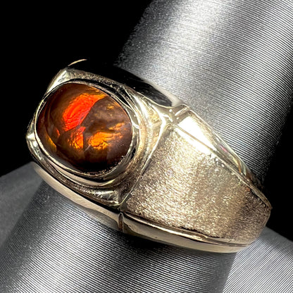 A yellow gold men's fire agate solitaire ring.  The fire agate is red with green undertones.