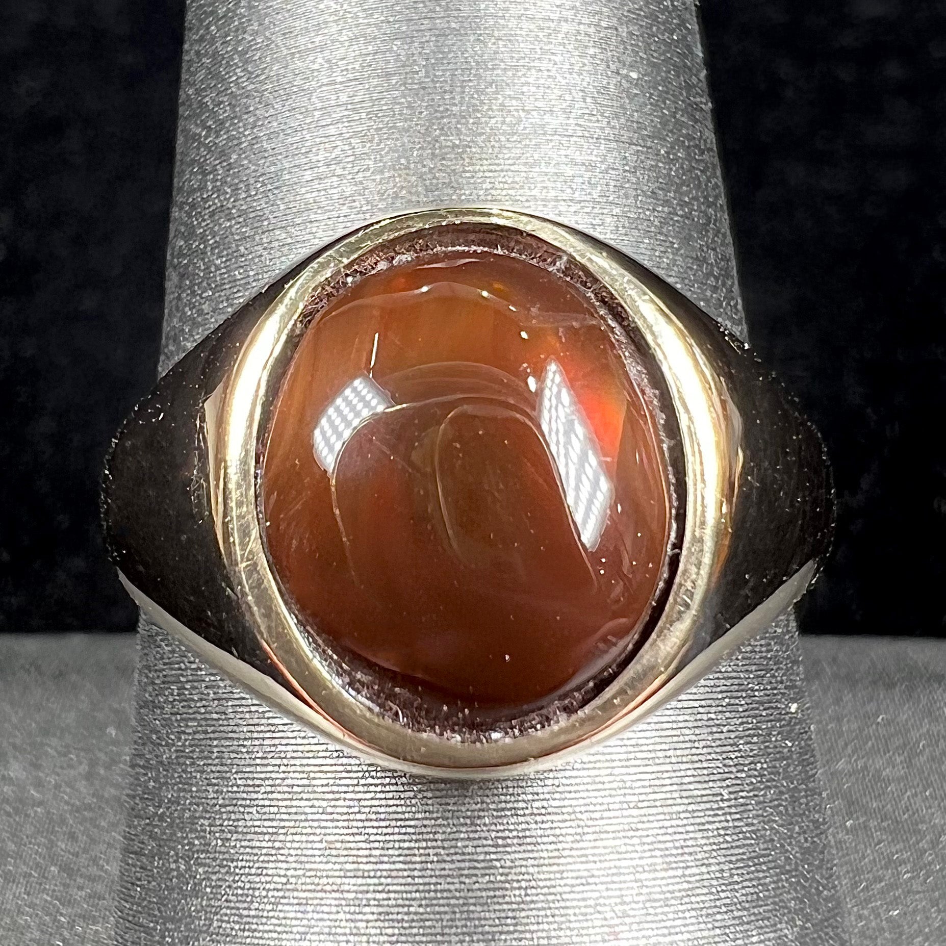 A unisex yellow gold flush set fire agate solitaire ring.