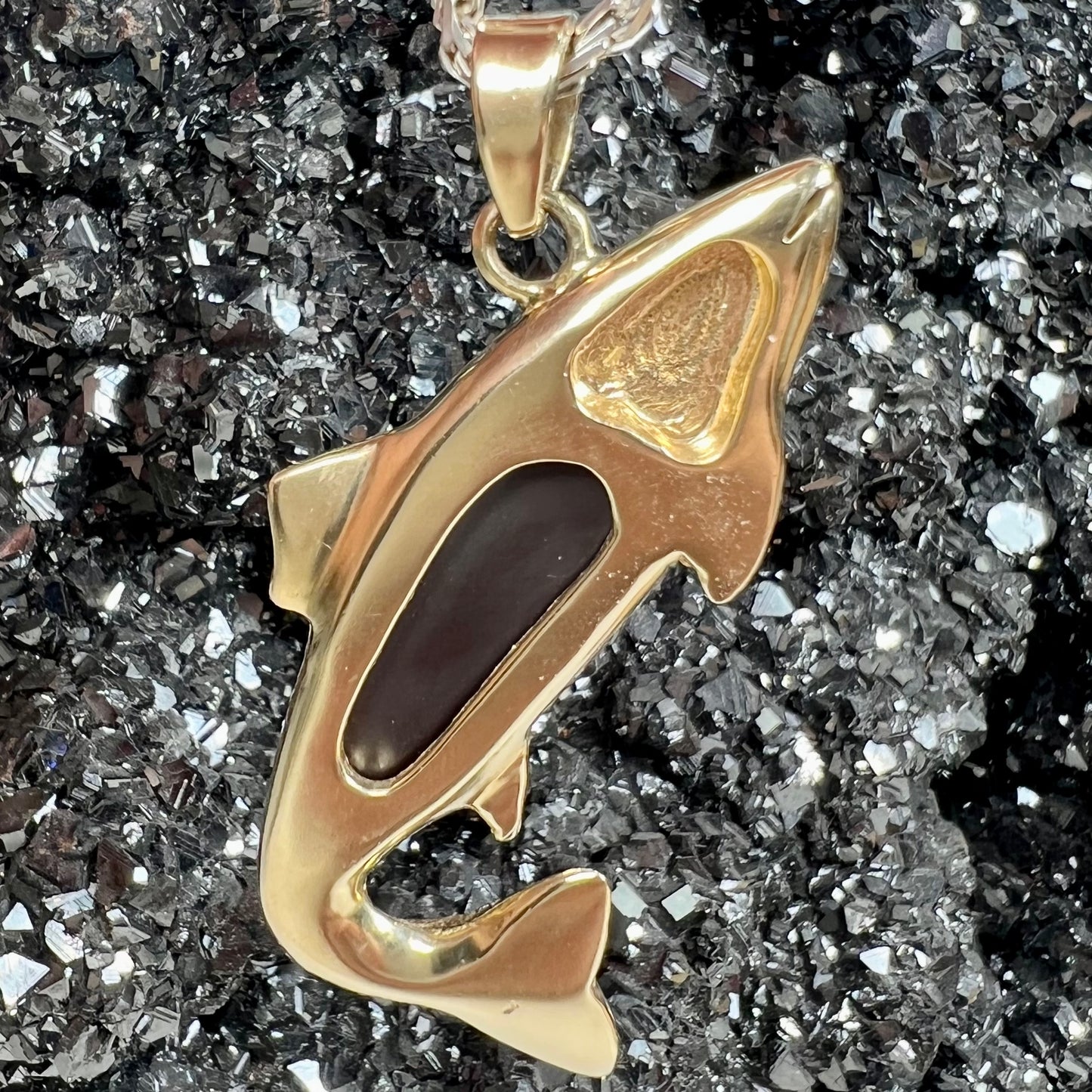 A yellow gold fish pendant detailed to look like a rainbow trout.  The body of the fish is set with a color changing black opal stone.