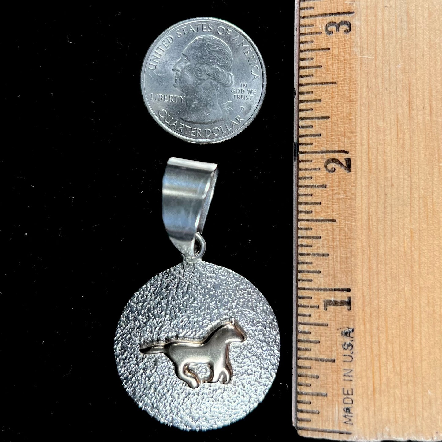 A Navajo-made sterling silver pendant depicting a yellow gold horse galloping.