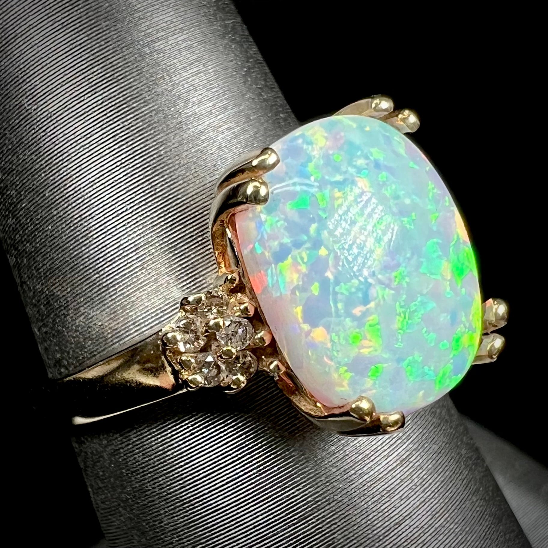 A ladies' yellow gold laboratory created, synthetic, cushion cut opal ring set with natural diamond accents.