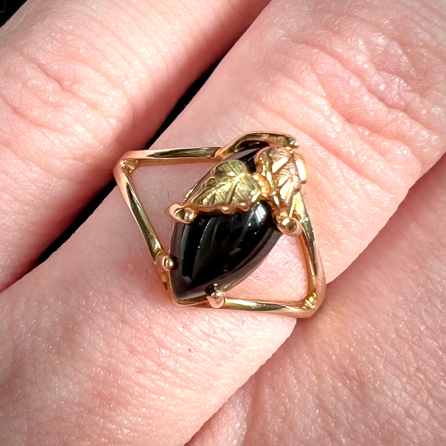 A split shank Black Hills gold ring set with a cabochon marquise cut black onyx.