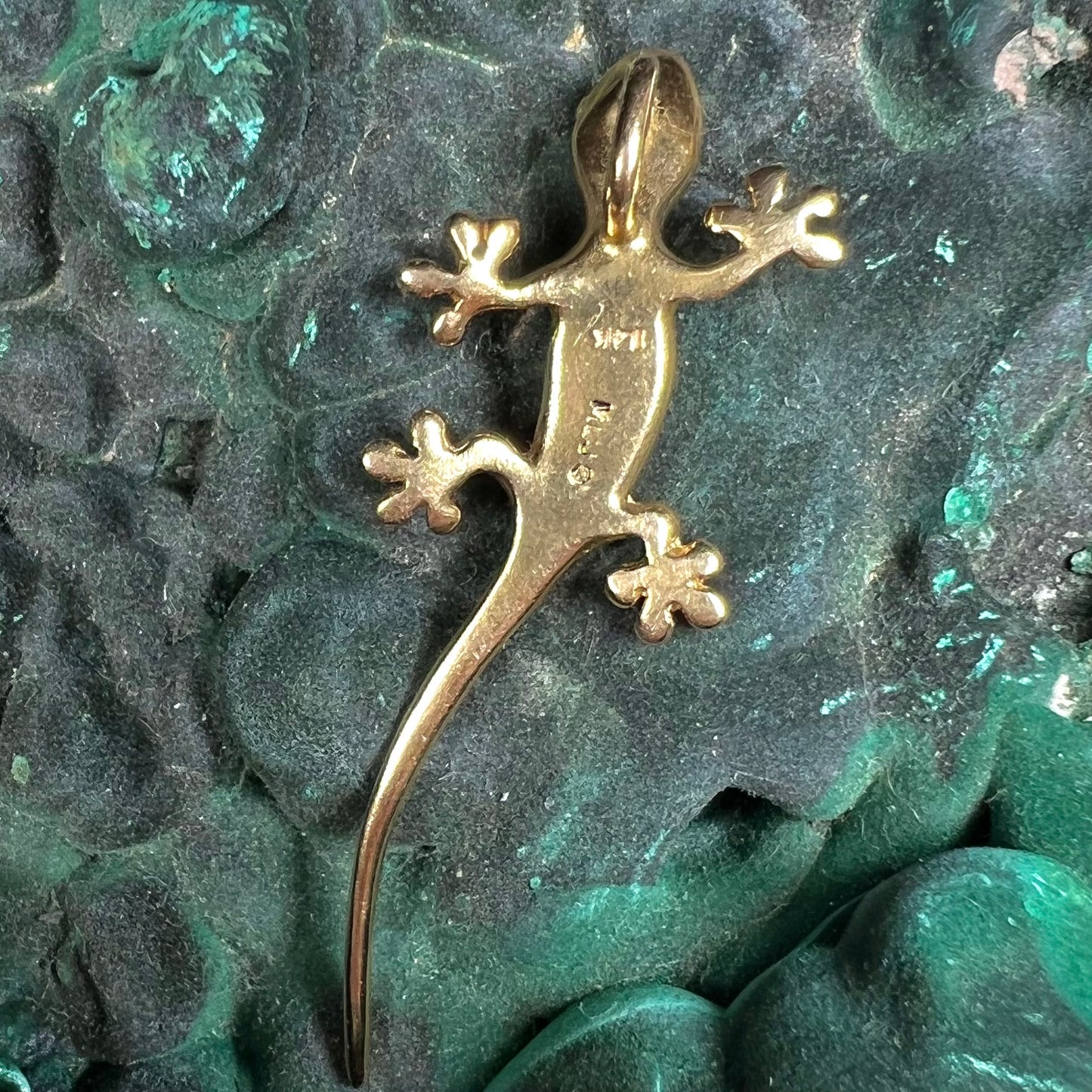 A solid yellow gold gecko lizard pendant with a hidden bail.