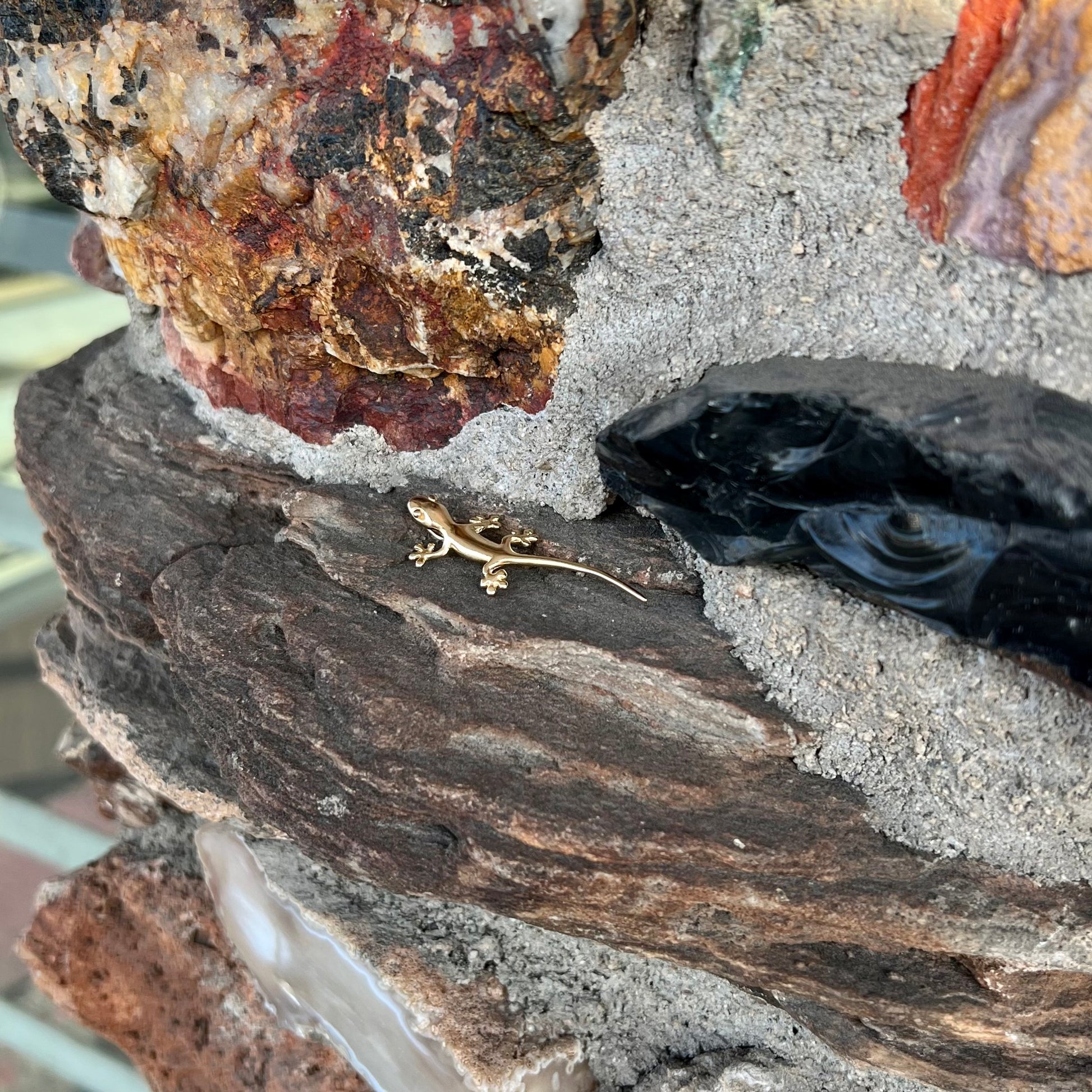 A solid yellow gold gecko lizard pendant with a hidden bail.
