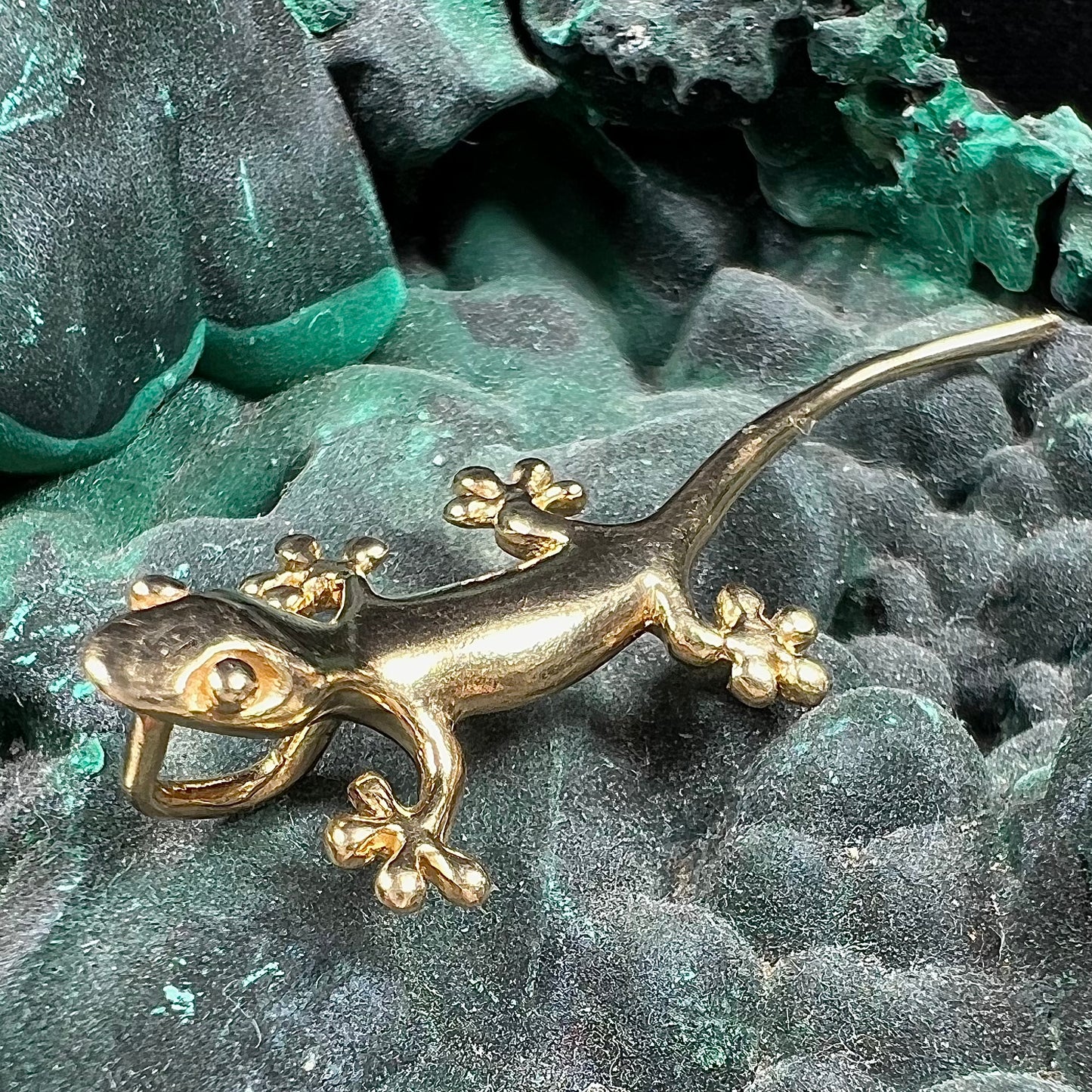 A solid yellow gold gecko lizard pendant with a hidden bail.