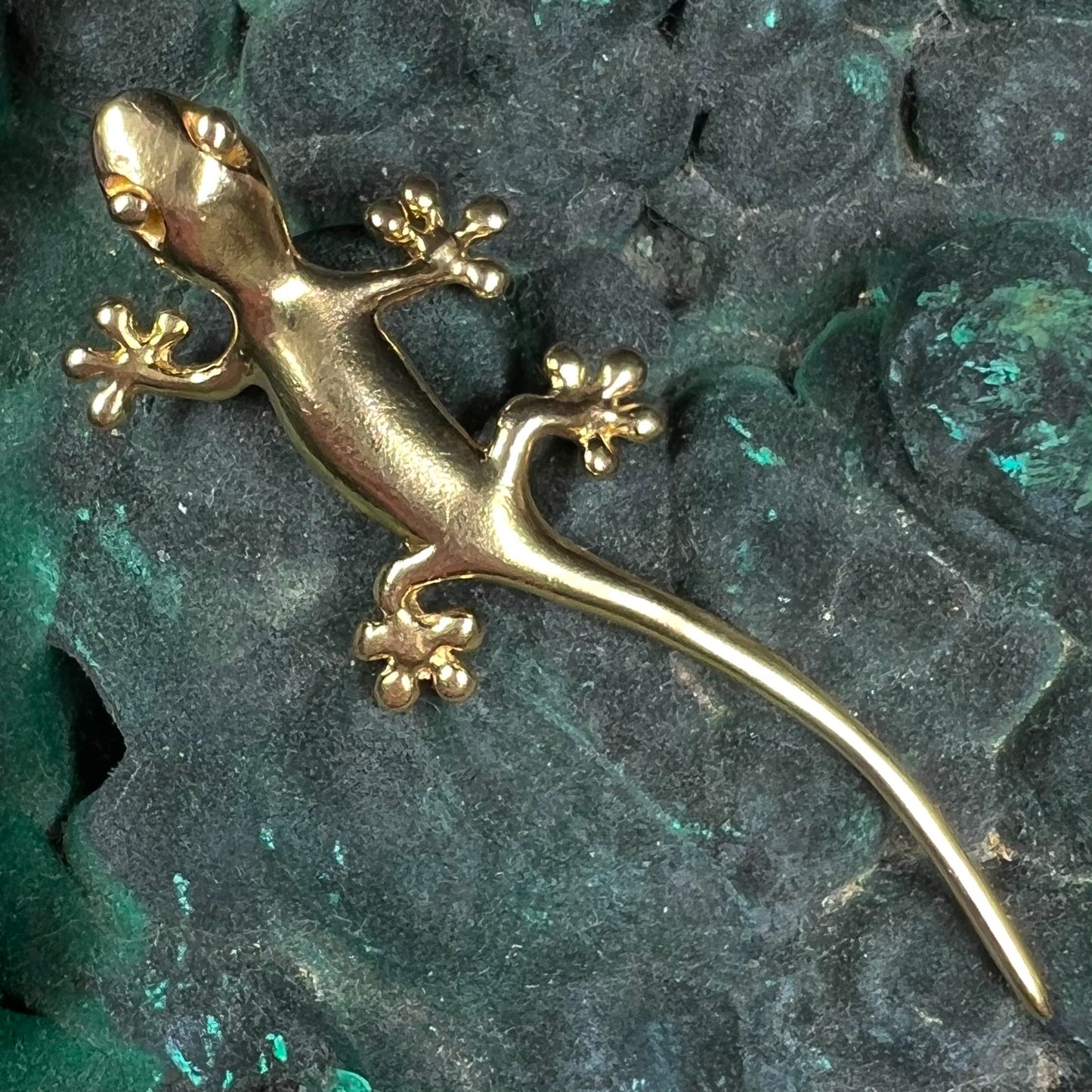 A solid yellow gold gecko lizard pendant with a hidden bail.