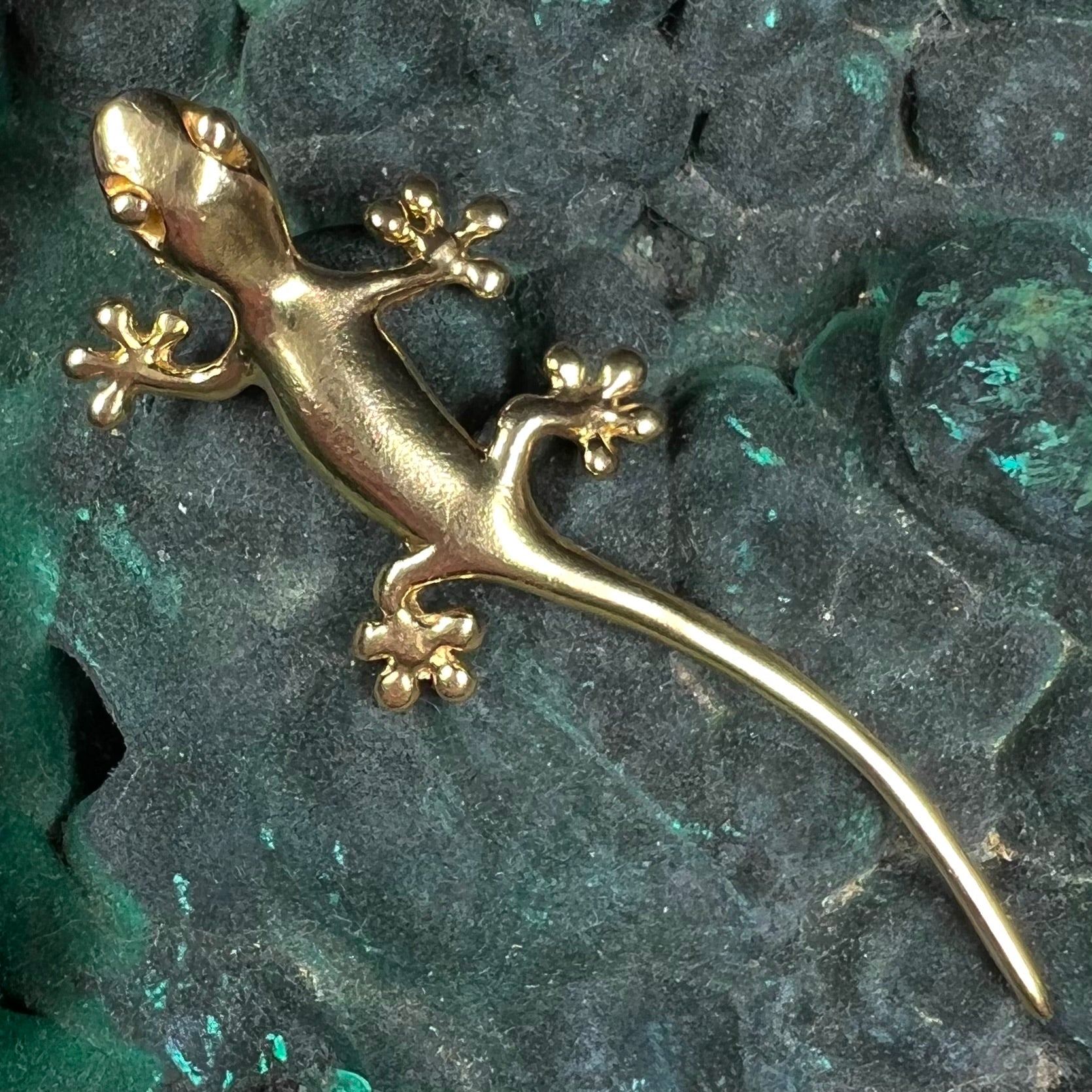 A solid yellow gold gecko lizard pendant with a hidden bail.